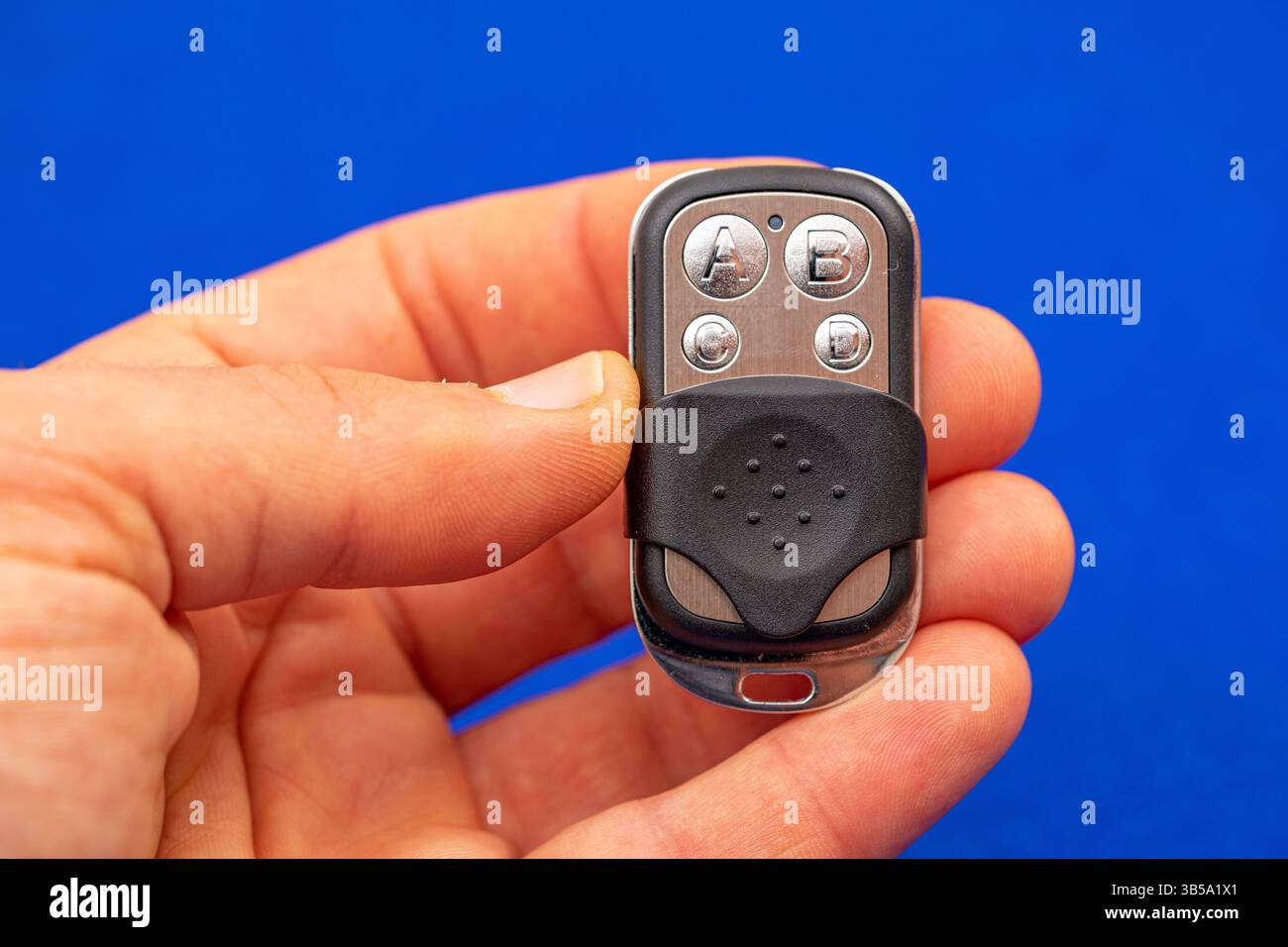 four-button remote control for opening garage doors held in hand on blue background Stock Photo