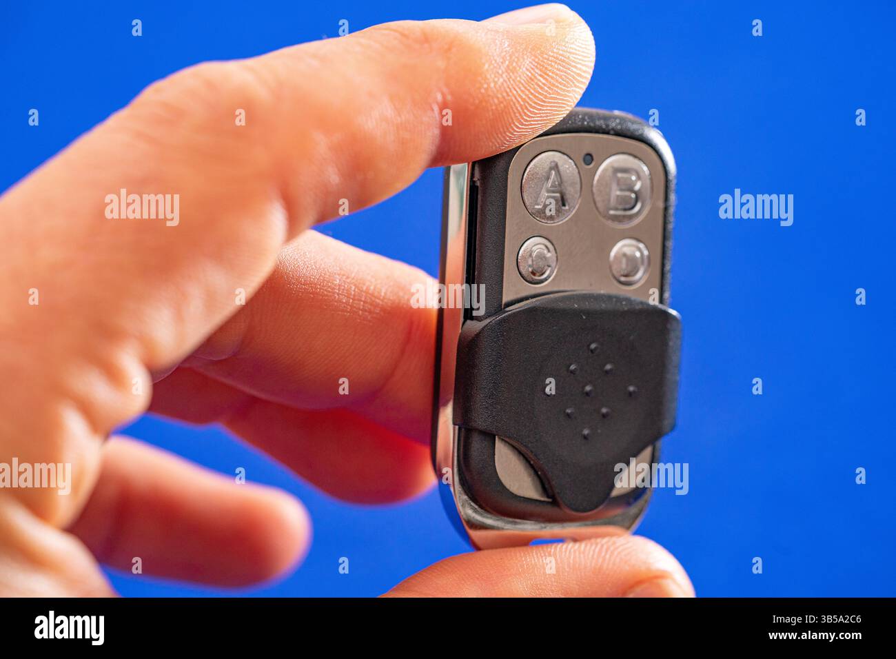 four-button remote control for opening garage doors held in hand on blue background Stock Photo