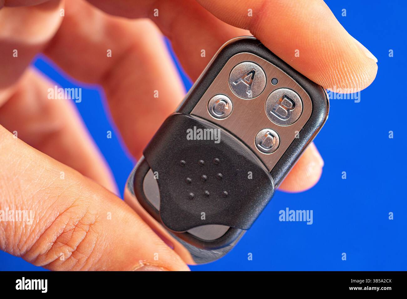 four-button remote control for opening garage doors held in hand on blue background Stock Photo