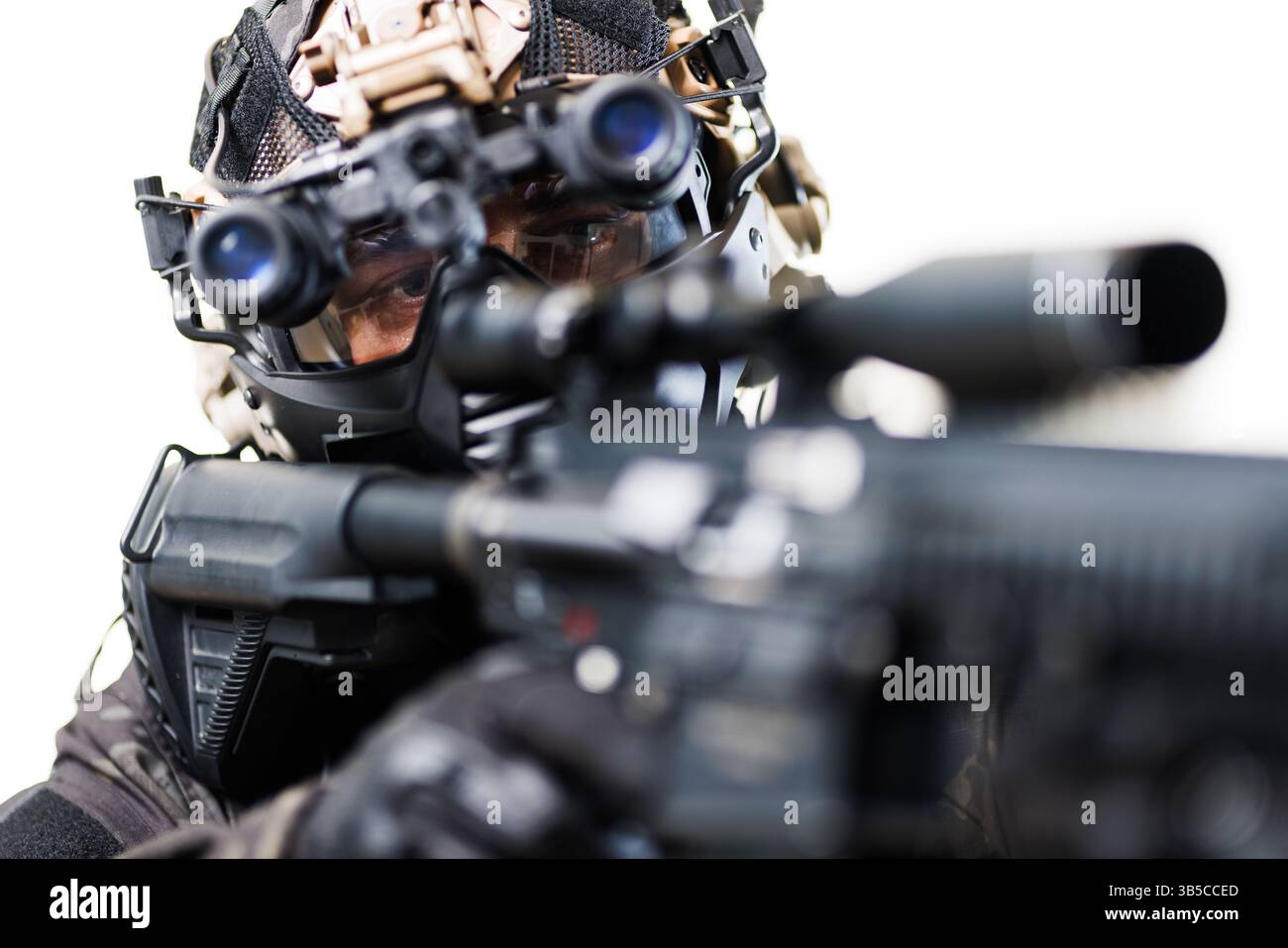 A focused tactical operative equipped with night vision goggles and aiming a weapon, exemplifying modern tactical gear and intense concentration in a Stock Photo