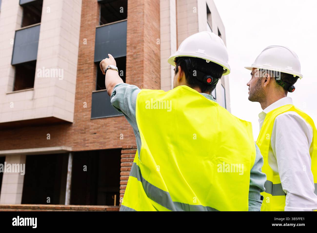 Engineers discussing building project at construction site Stock Photo