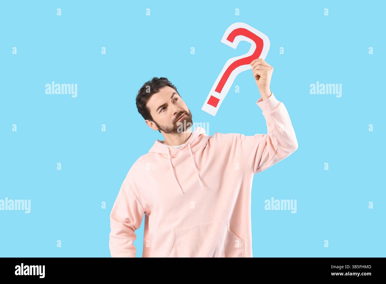 Thoughtful man with question mark on blue background Stock Photo