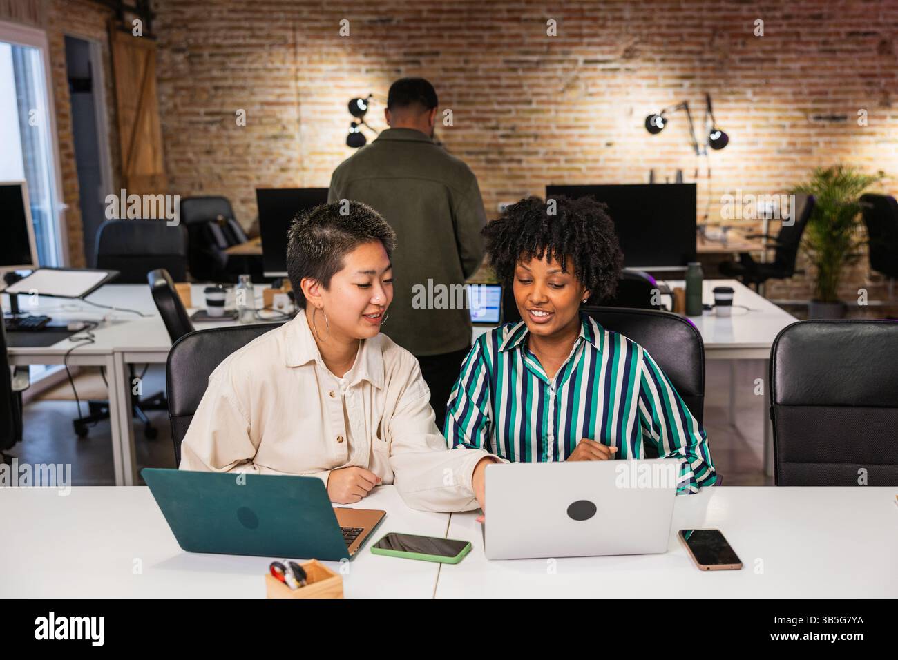 Multi ethnic team working together on project using laptops in modern office Stock Photo
