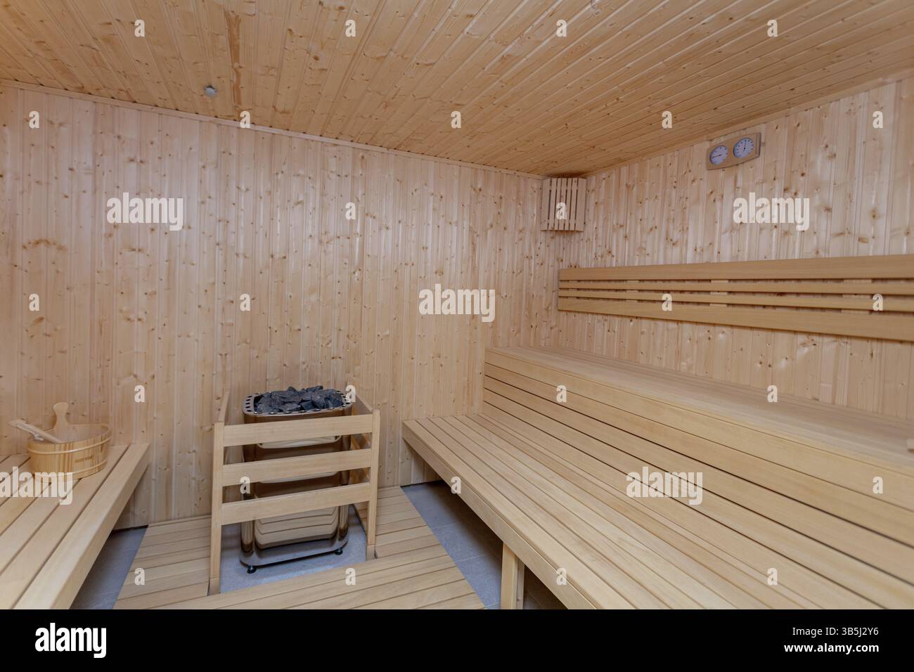 Enjoy the calming ambiance of a wooden sauna interior with traditional benches and a wellnessfocused heater Stock Photo