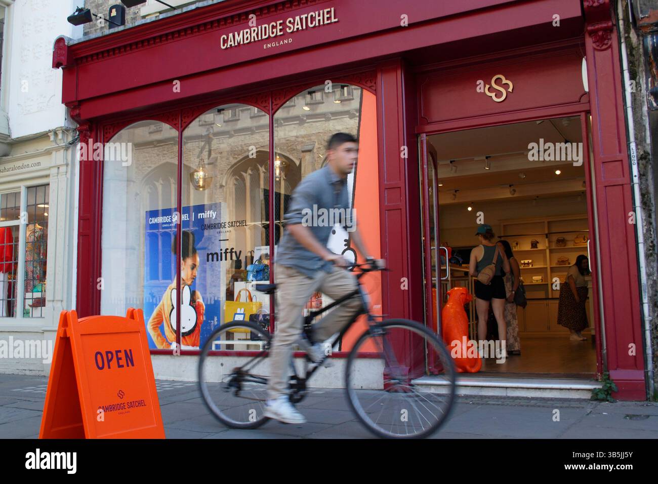 Cyclists passing by the Cambridge Satchel store on St Mary's Passage in Cambridge's historic city centre. England, UK. 2025 Stock Photo