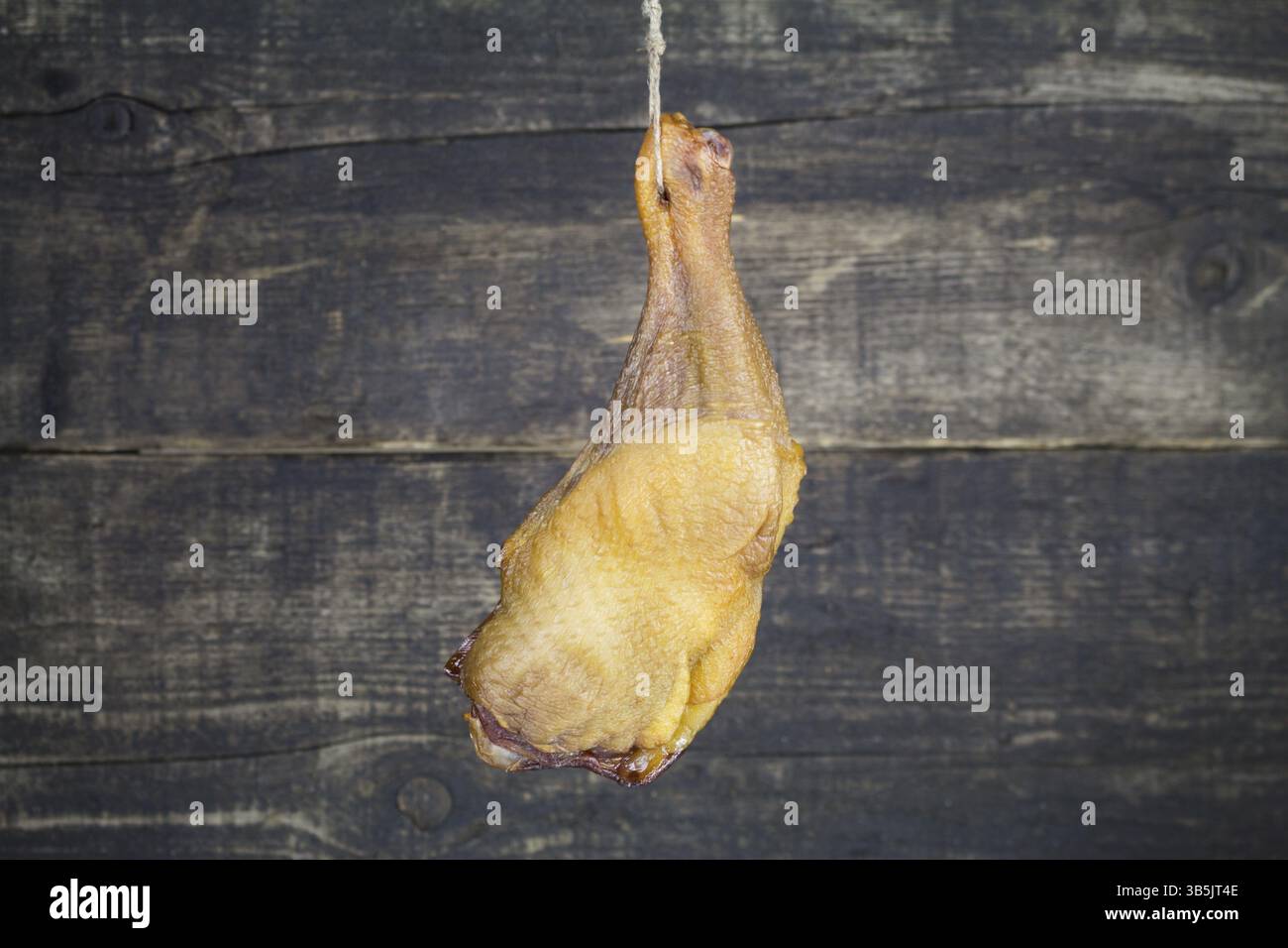 Smoked Chicken Leg Hanging on the Rope Against Wooden Background Stock ...
