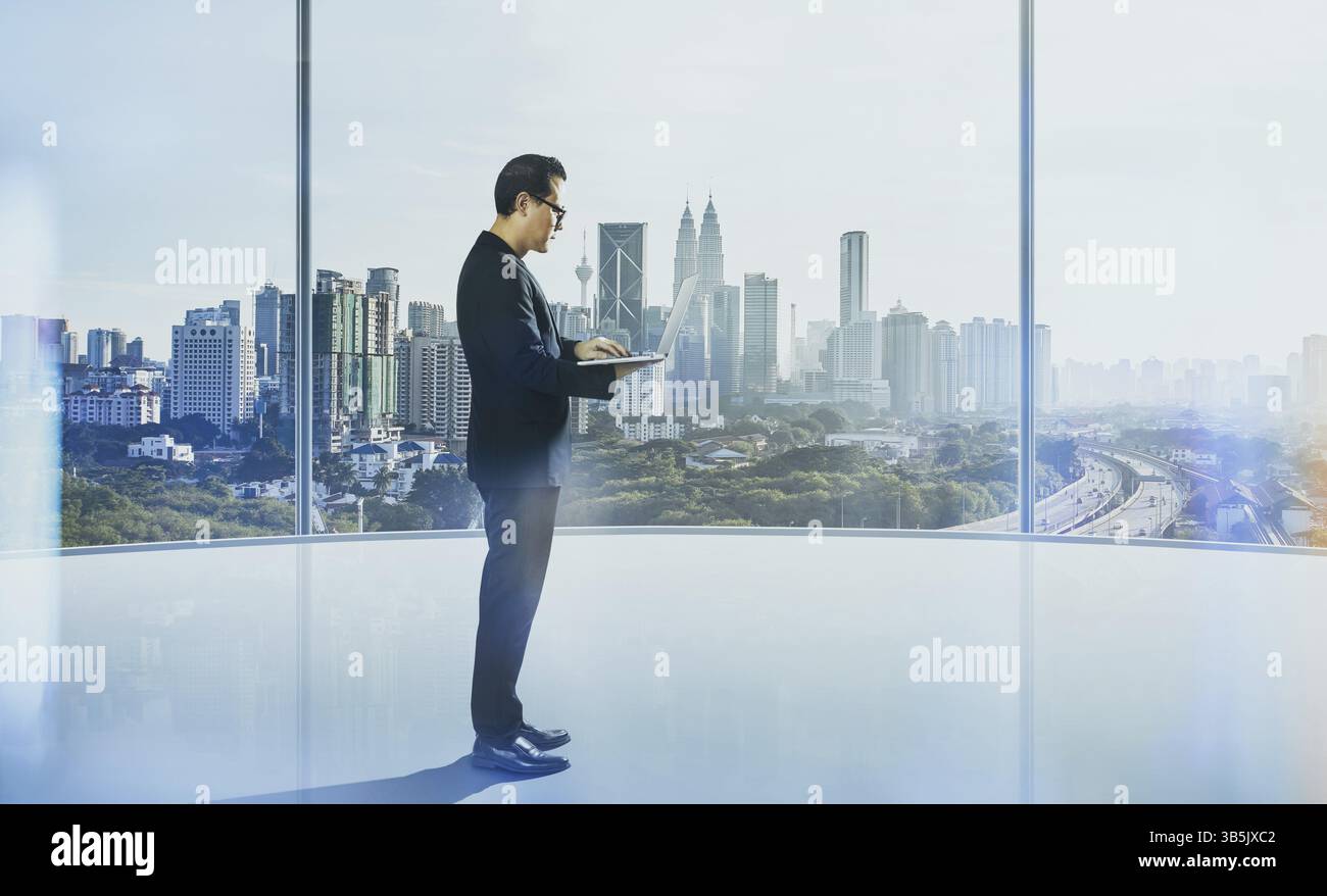 Businessman using laptop with generic office background, night scene Stock Photo