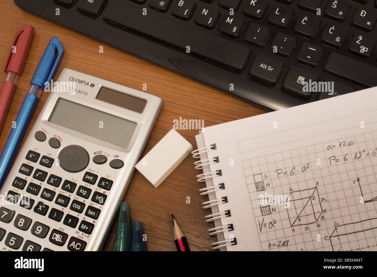 Computer keyboard, colorful pencils, eraser and notebook on the table Stock Photo