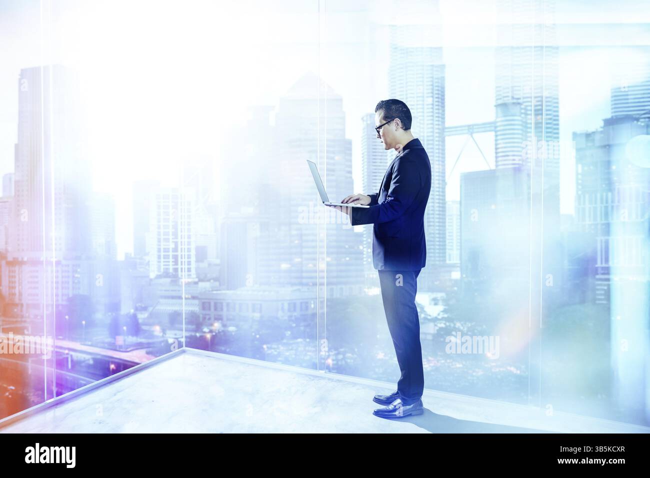 Businessman using laptop with generic office background, night scene Stock Photo