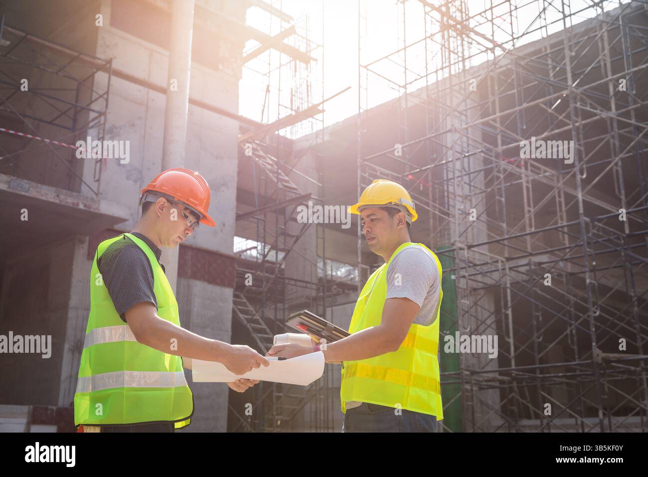 Engineer discussing with foreman about project in building construction site. Stock Photo