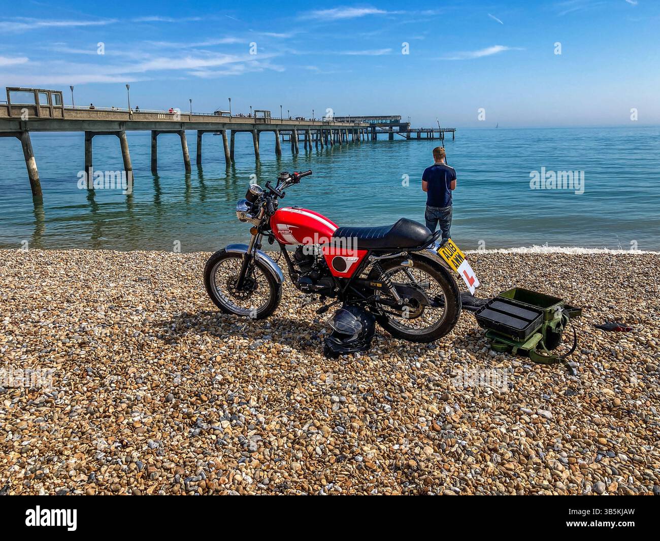 Young Man, with his Mash 50 motorcycle,  fishing off the beach, next to Deal Pier on May Day 2025 Stock Photo