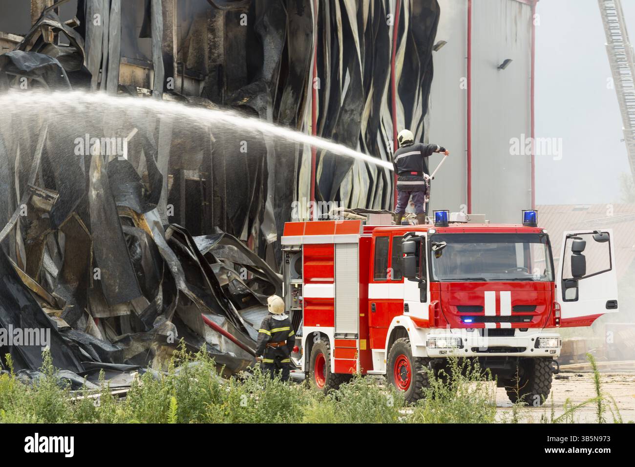 Fire disaster in a warehouse. Fire fighting in an industrial area. Red fire truck Stock Photo