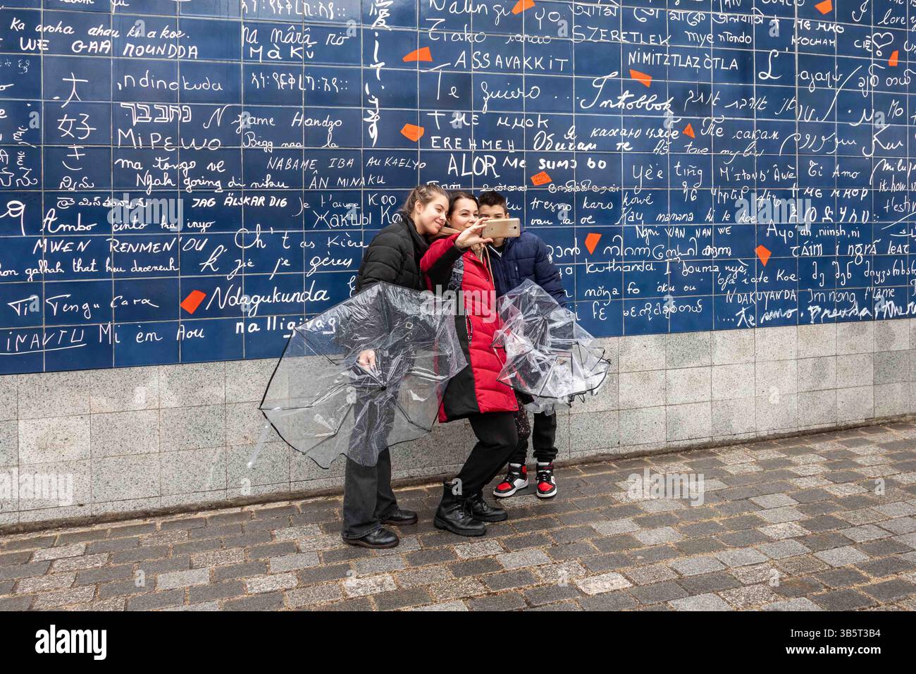 Tourists taking selfies with Le Mur des Je Taime or Wall of I Love You at Square Jean Rictus in Montmartre district of Paris, France Stock Photo