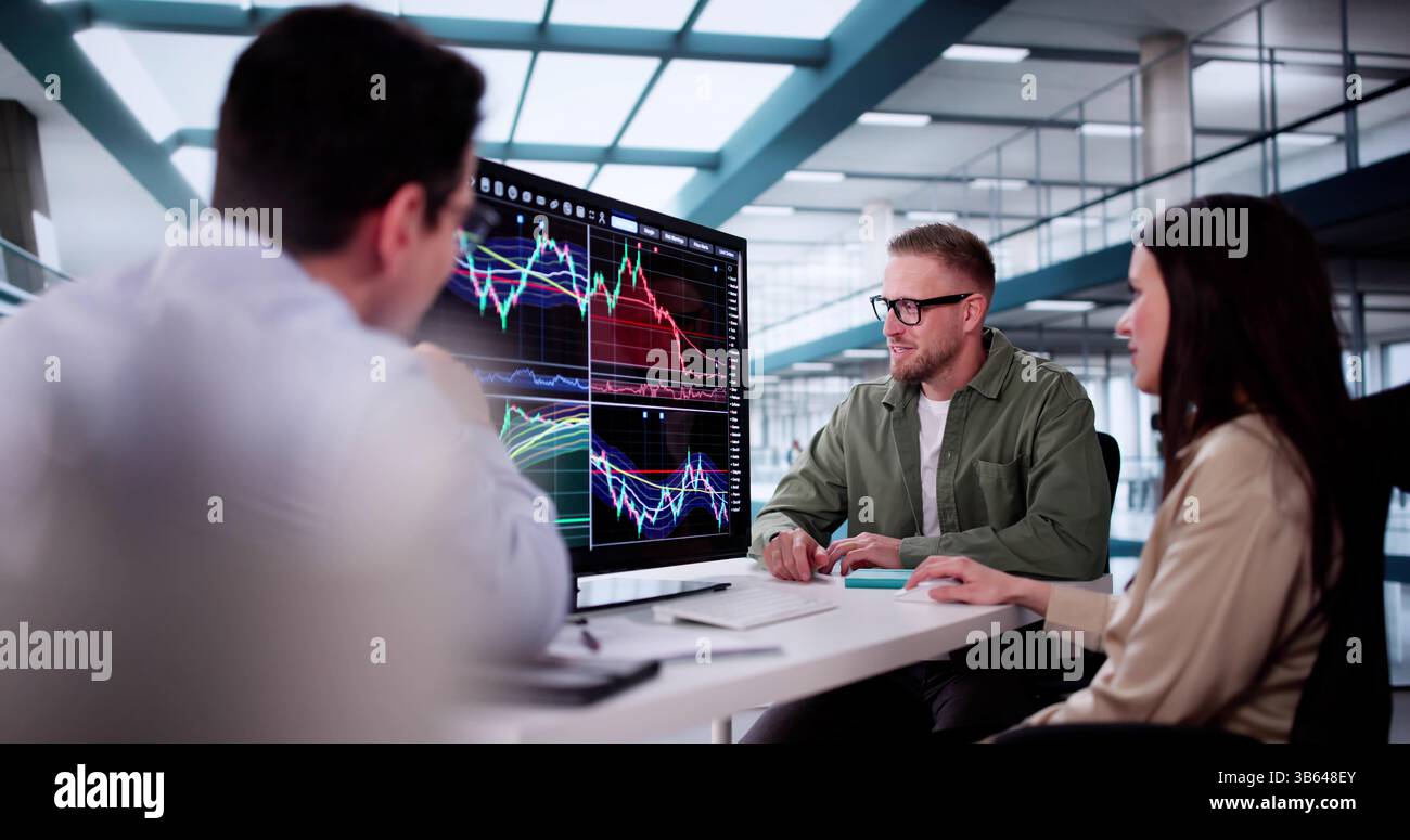 Financial Analysts Analyzing Stock Charts On Computer Screens In Office Setting. Stock Photo
