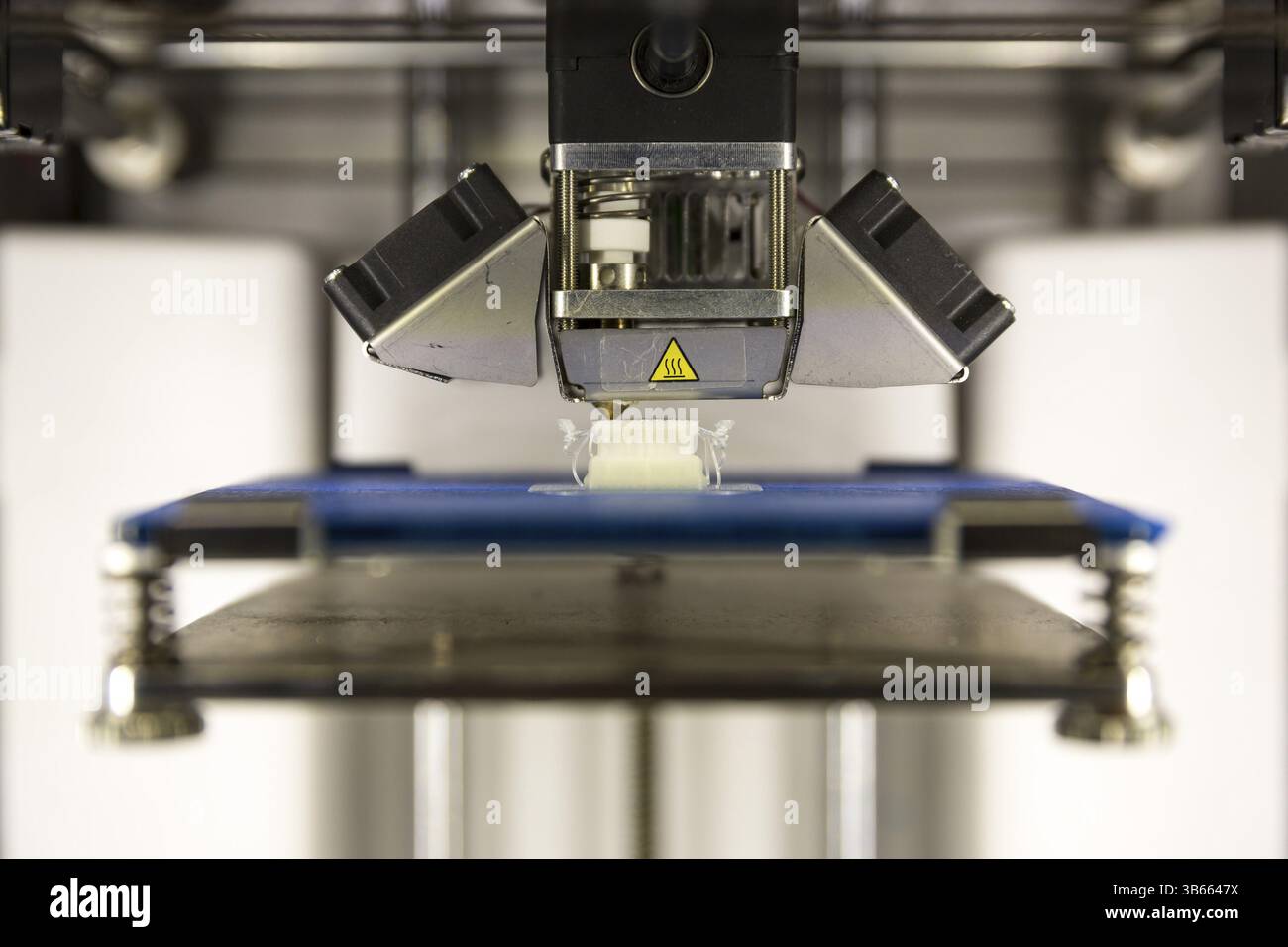 A 3D printer prints a white plastic detail. Three dimensional printing machine Stock Photo
