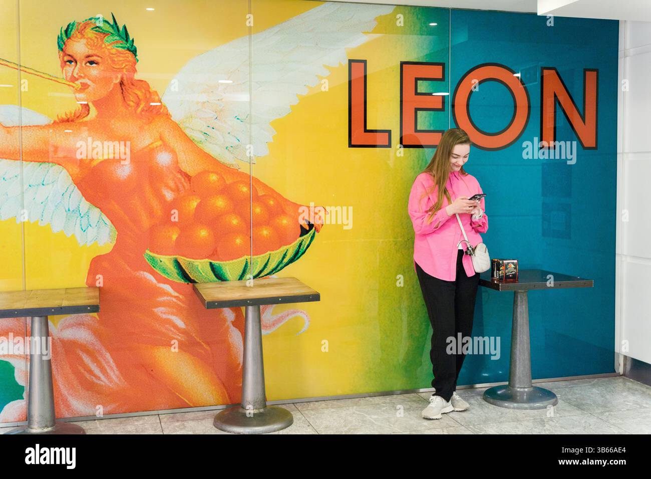 Woman using LEON mobile app ordering fast food in London UK Stock Photo