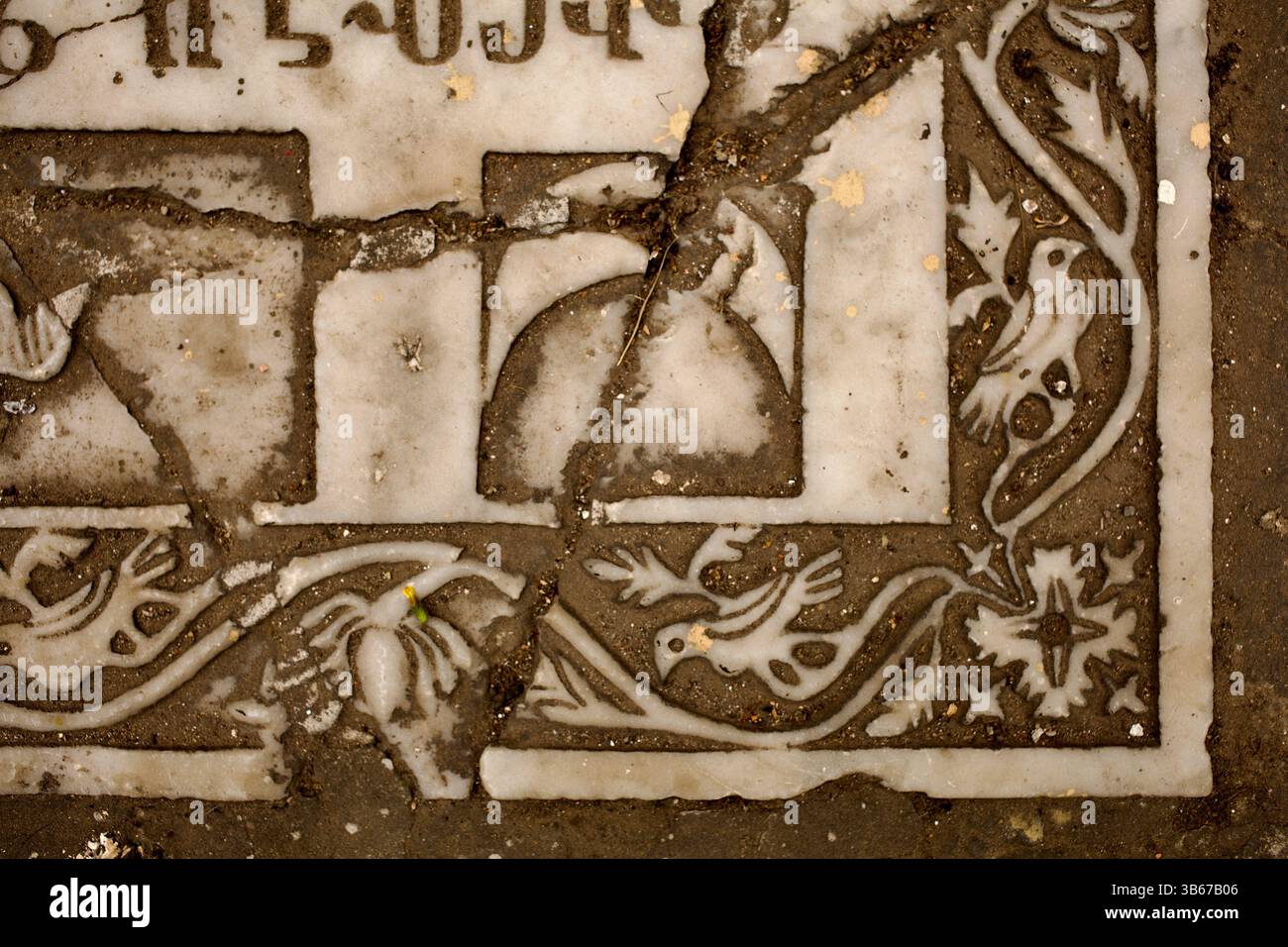 Detail of a cracked Armenian tombstone in Old Dhaka's Armanitola district showing bird and floral reliefs carved into white stone. Stock Photo