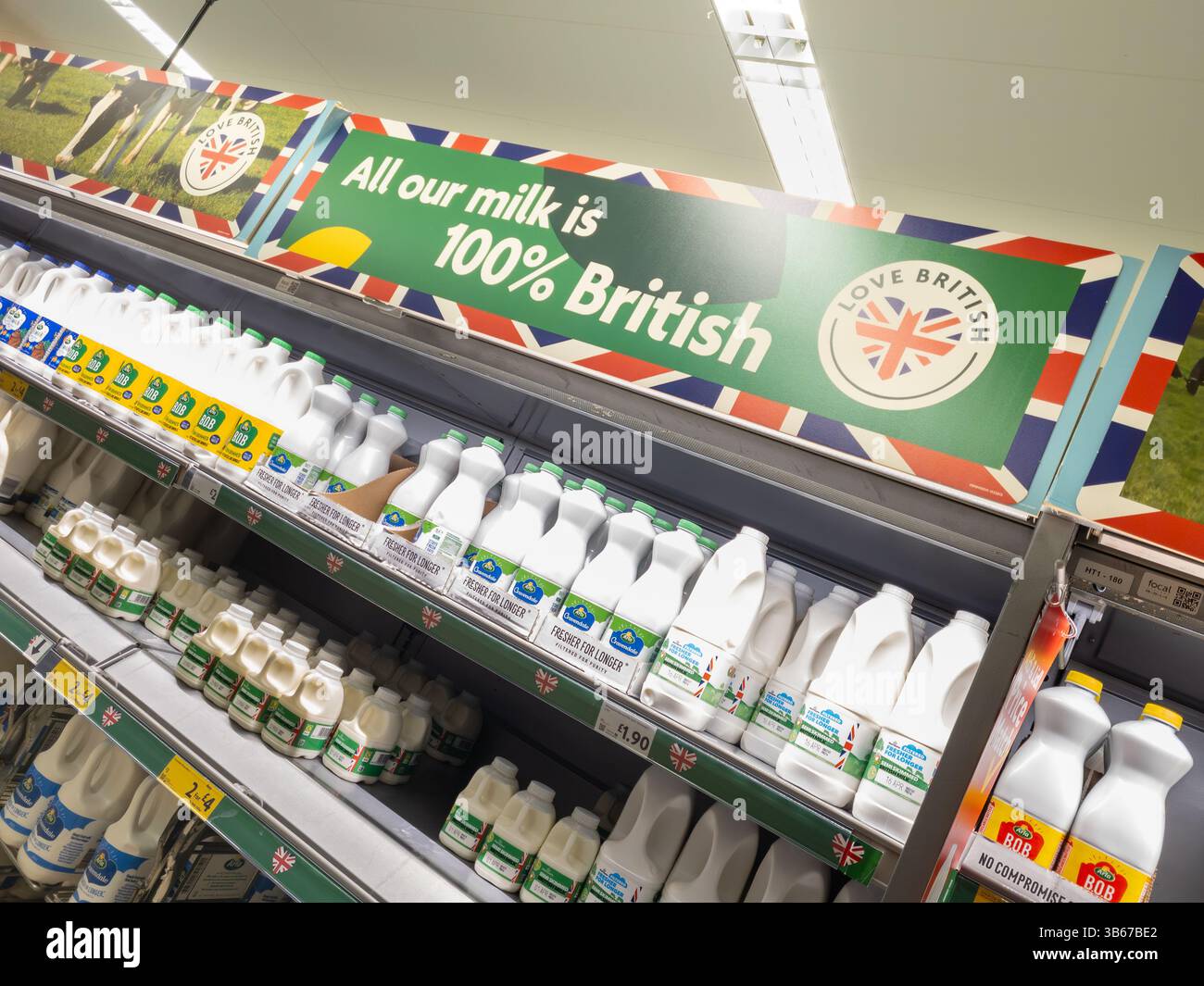 Milk on shelves at Tesco with 'Love British' logo and sign stating all our milk is 100% British, UK. Concept: supermarket milk, milk suppliers - Smartphone Captured Stock Image
