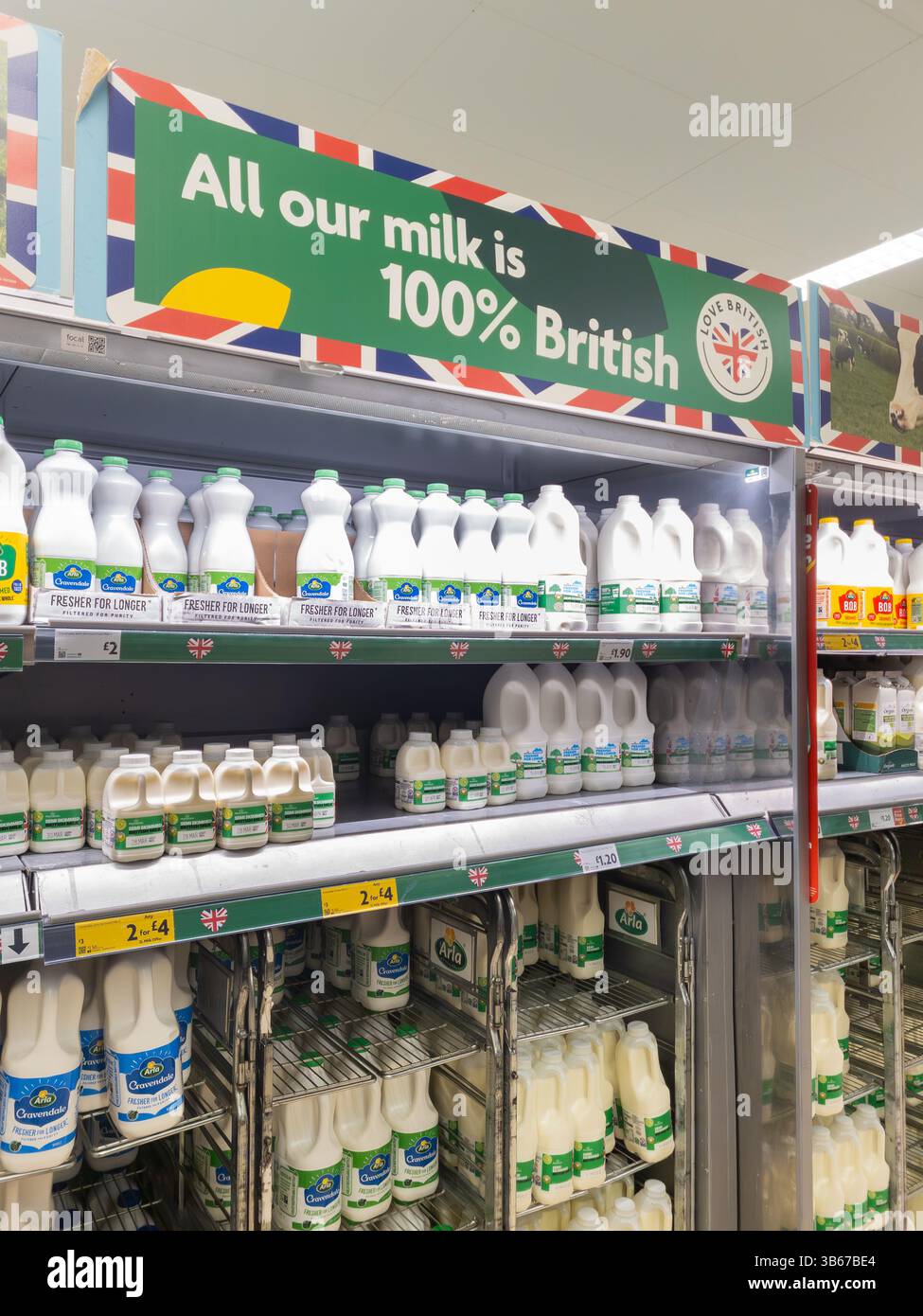 Milk on shelves at Tesco with 'Love British' logo and sign stating all our milk is 100% British, UK. Concept: supermarket milk, milk suppliers - Smartphone Captured Stock Image