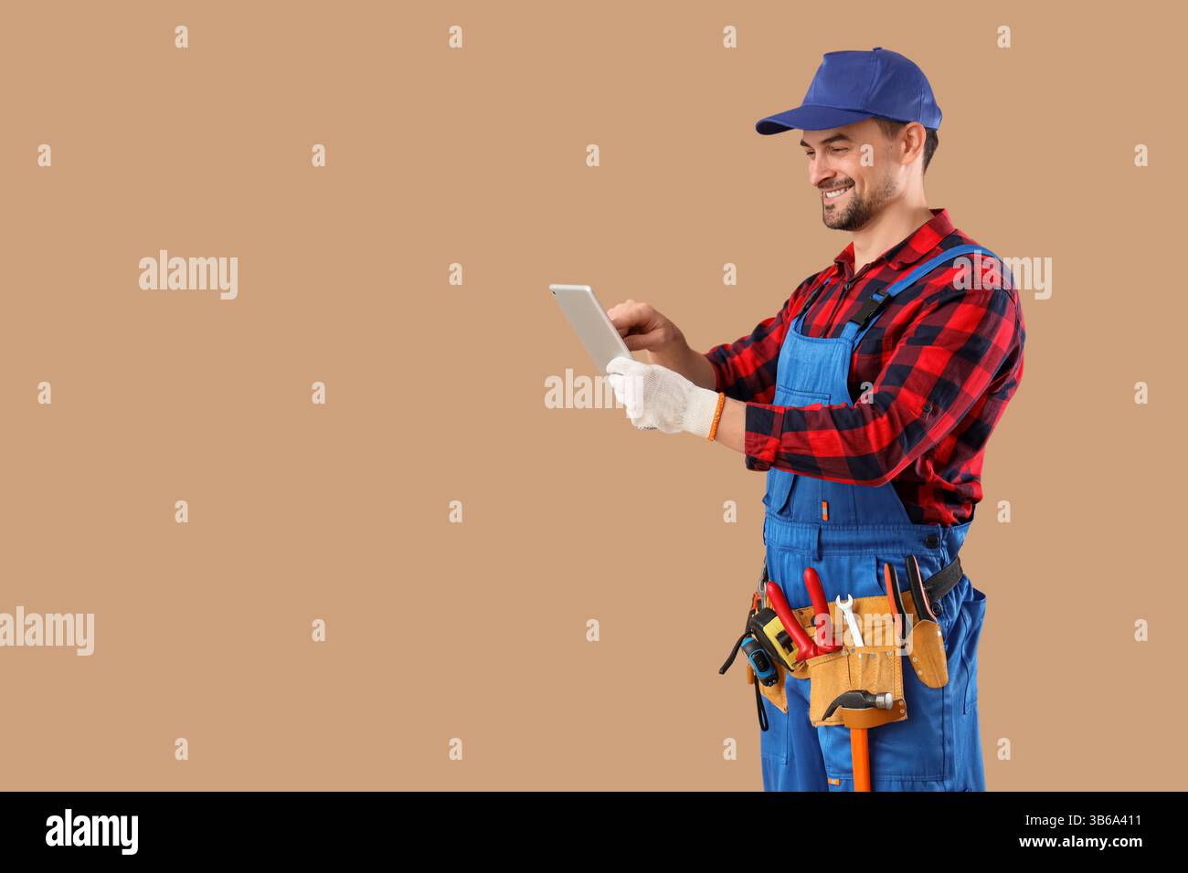 Male technician using tablet computer on beige background Stock Photo