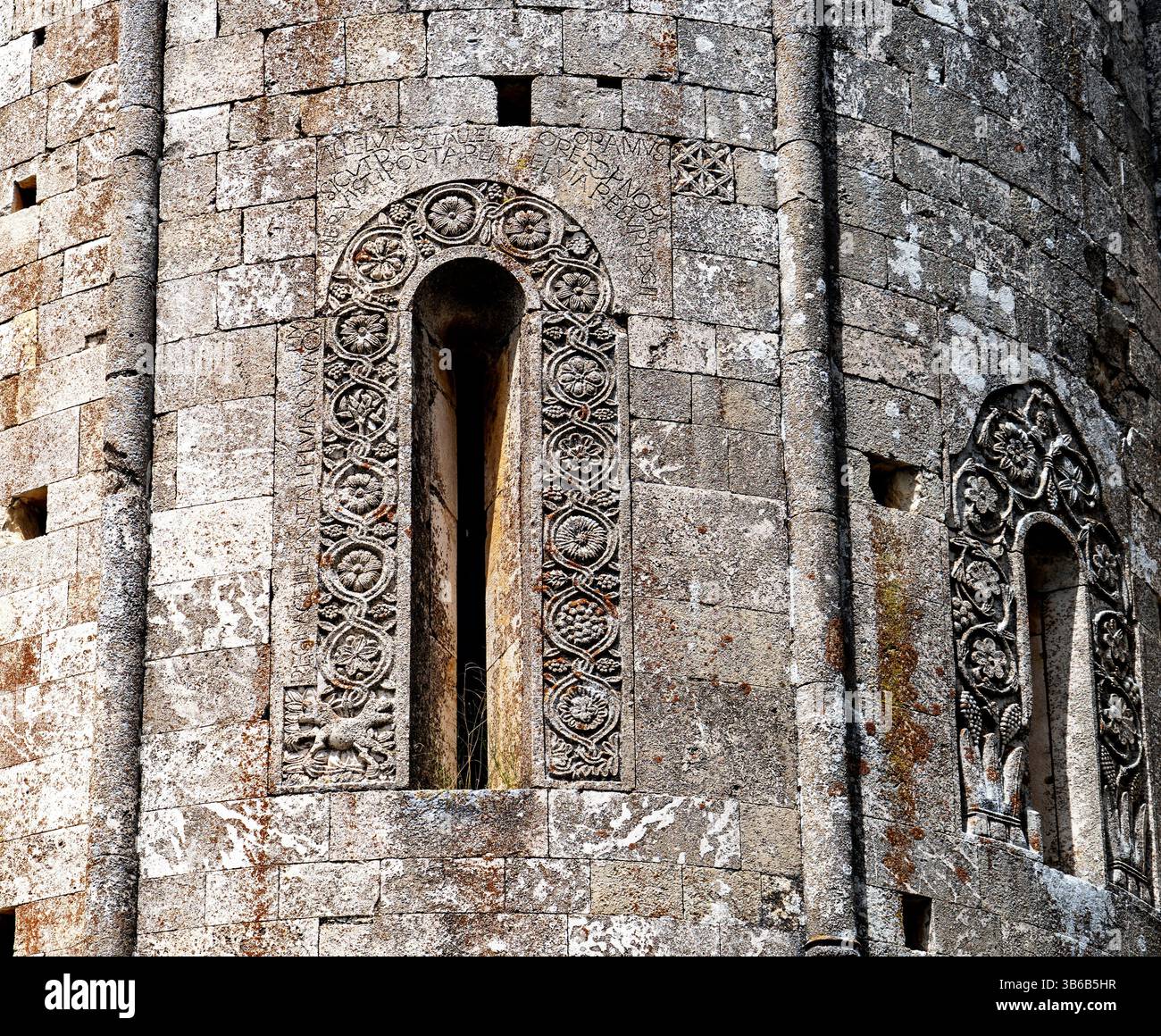 Close-up of ancient stone architecture featuring intricately carved window frames and textured stone walls, showcasing historical craftsmanship and de Stock Photo