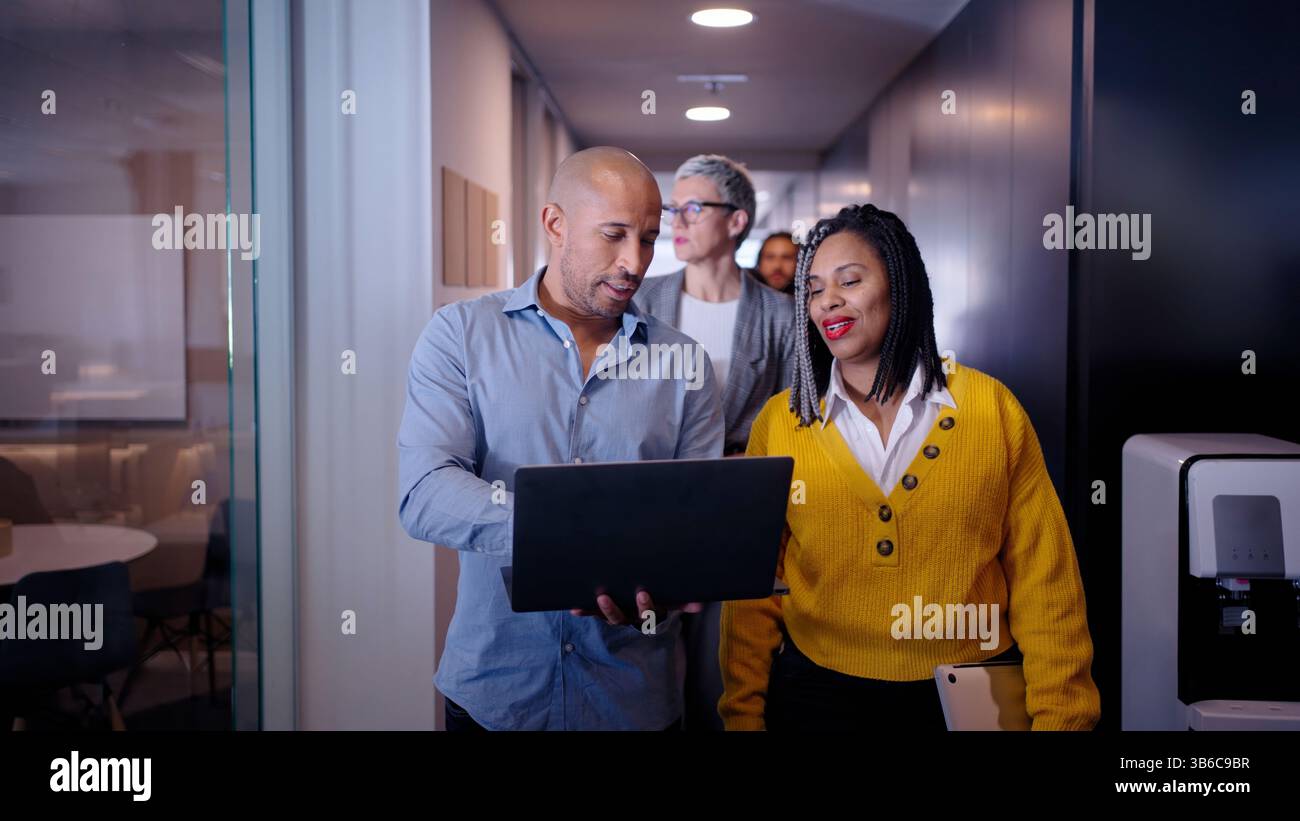 Business colleagues walking and talking in office corridor Stock Photo