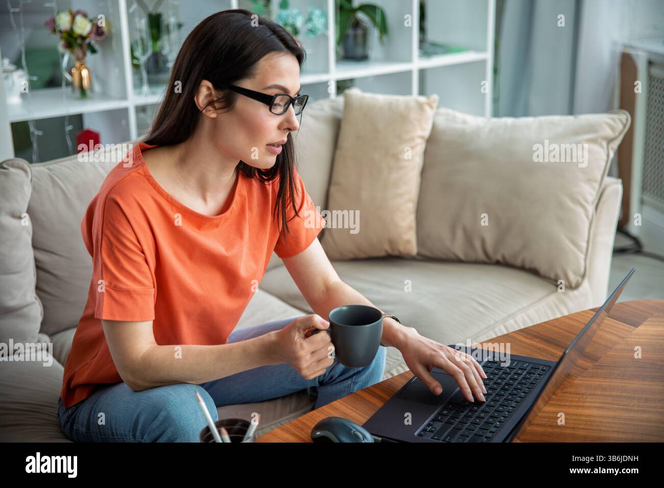 Woman using laptop and drinking coffee Stock Photo