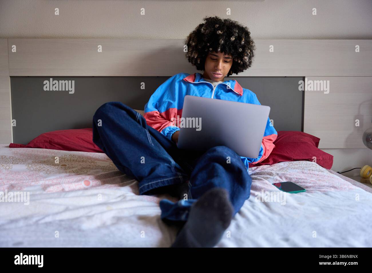 Young student using laptop on bed at home Stock Photo