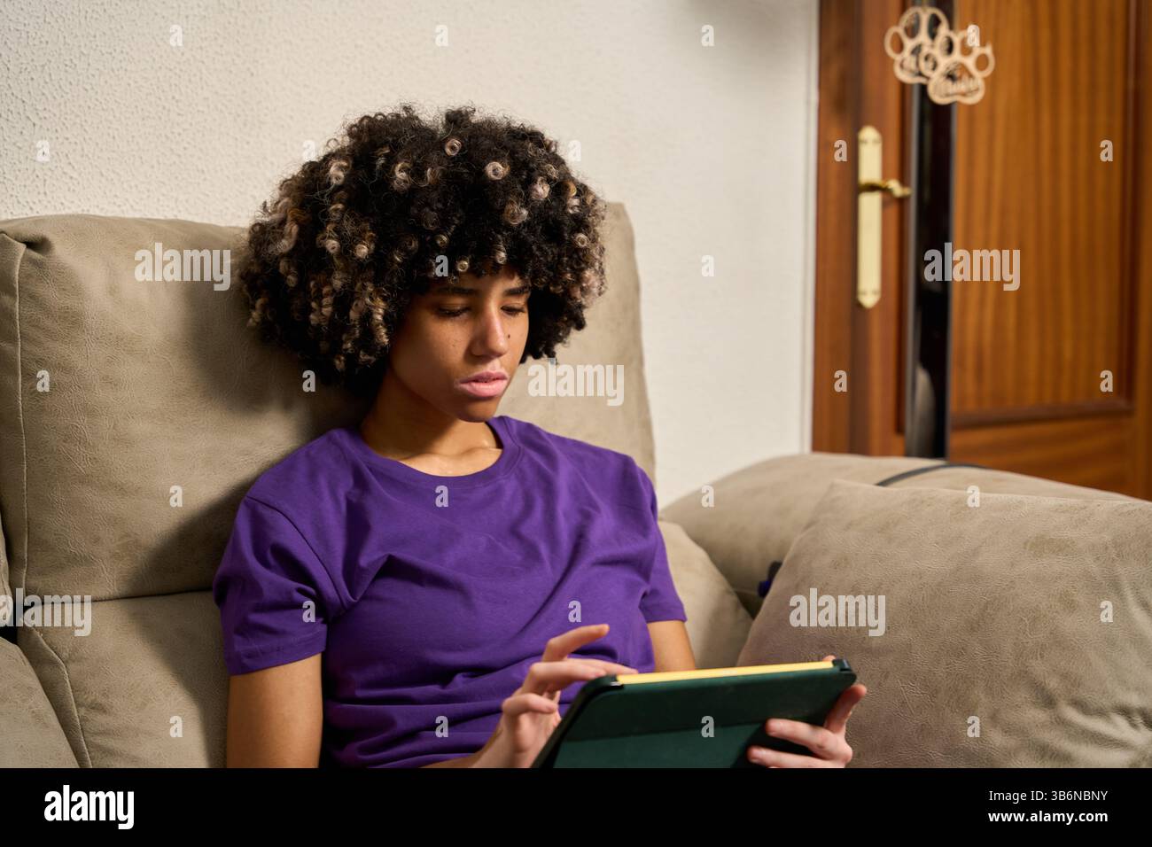 Female student using digital tablet on sofa at home Stock Photo
