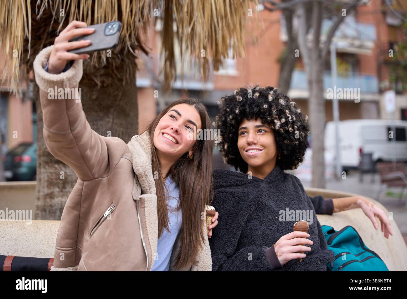 University students taking selfie while eating ice cream outdoors Stock Photo