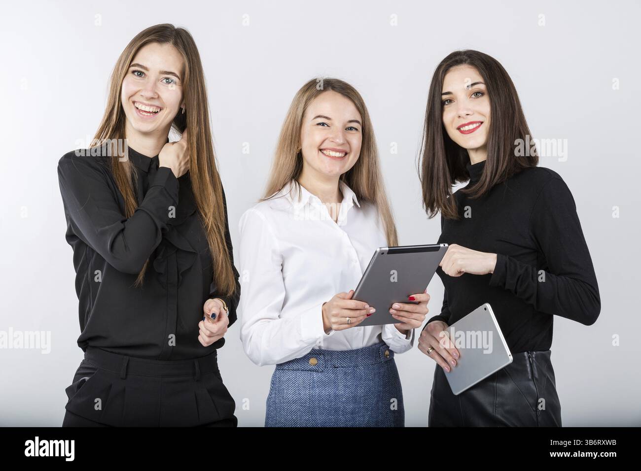 Three smiling business women standing in a row isolated on white ...