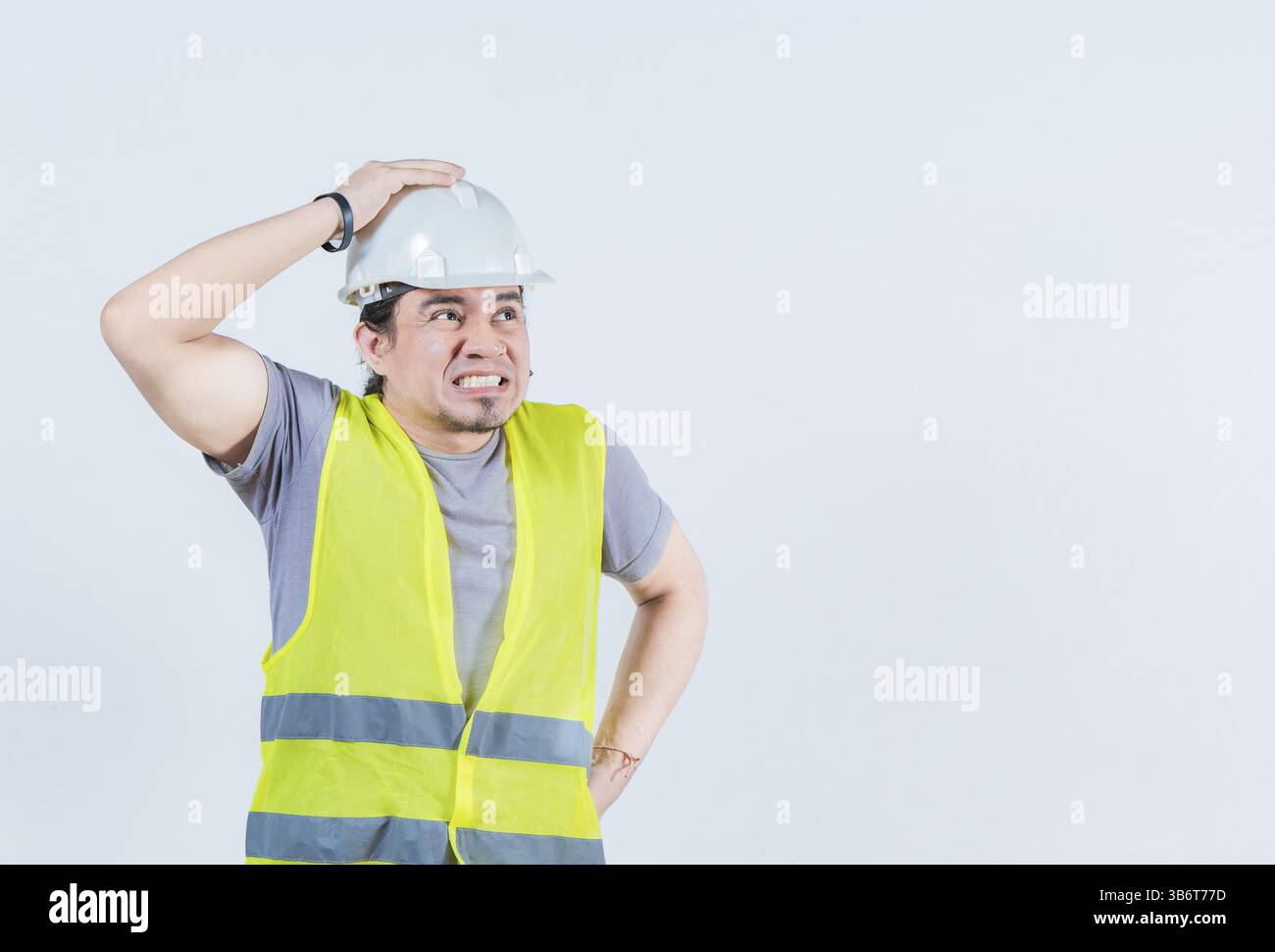 Constructor worker in problems holding head isolated. Worried builder engineer holding head. Troubled young engineer holding head Stock Photo