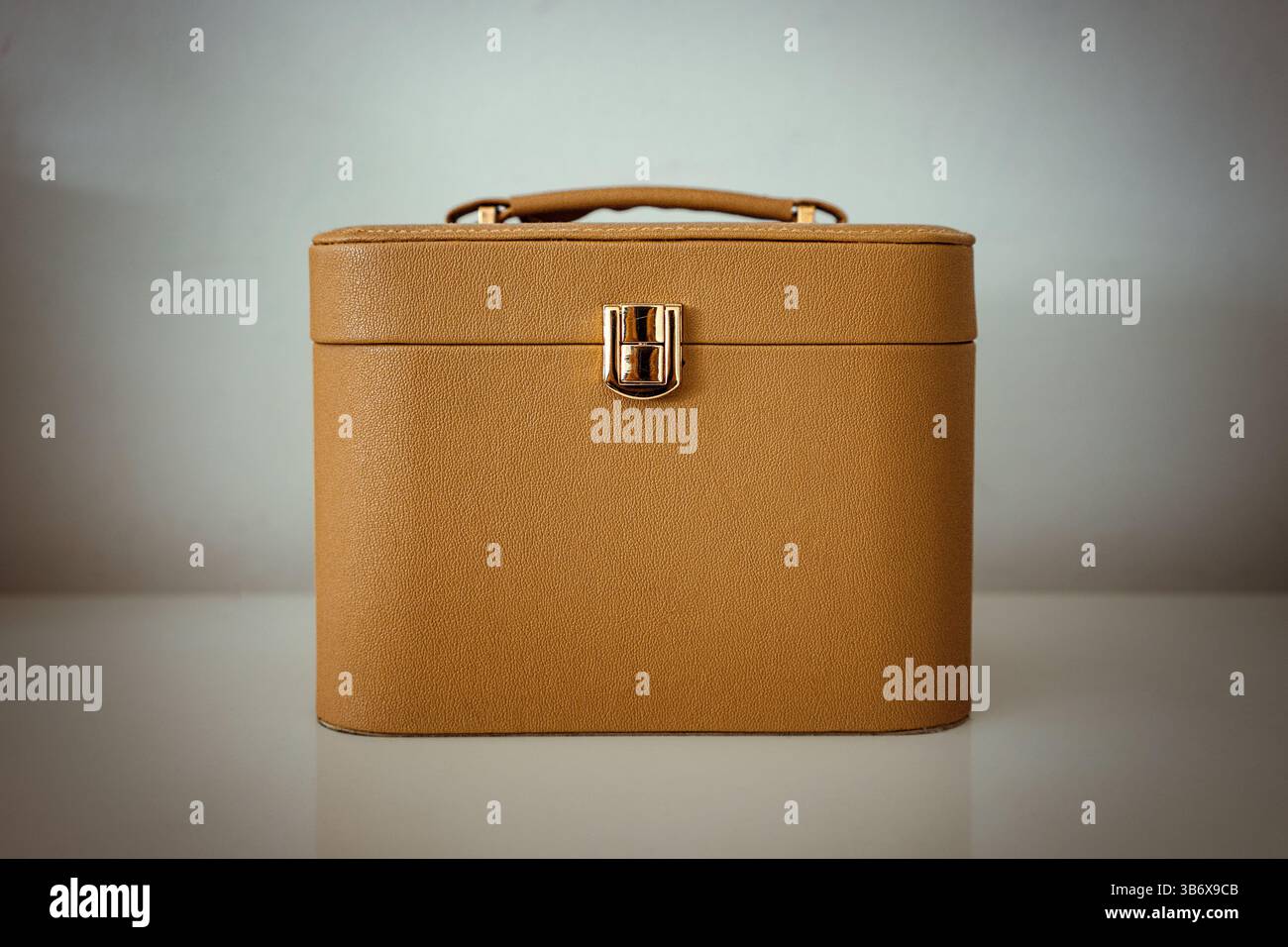 Details of a brown luxury cosmetic bag on a white table in front of a white wall. Stock Photo