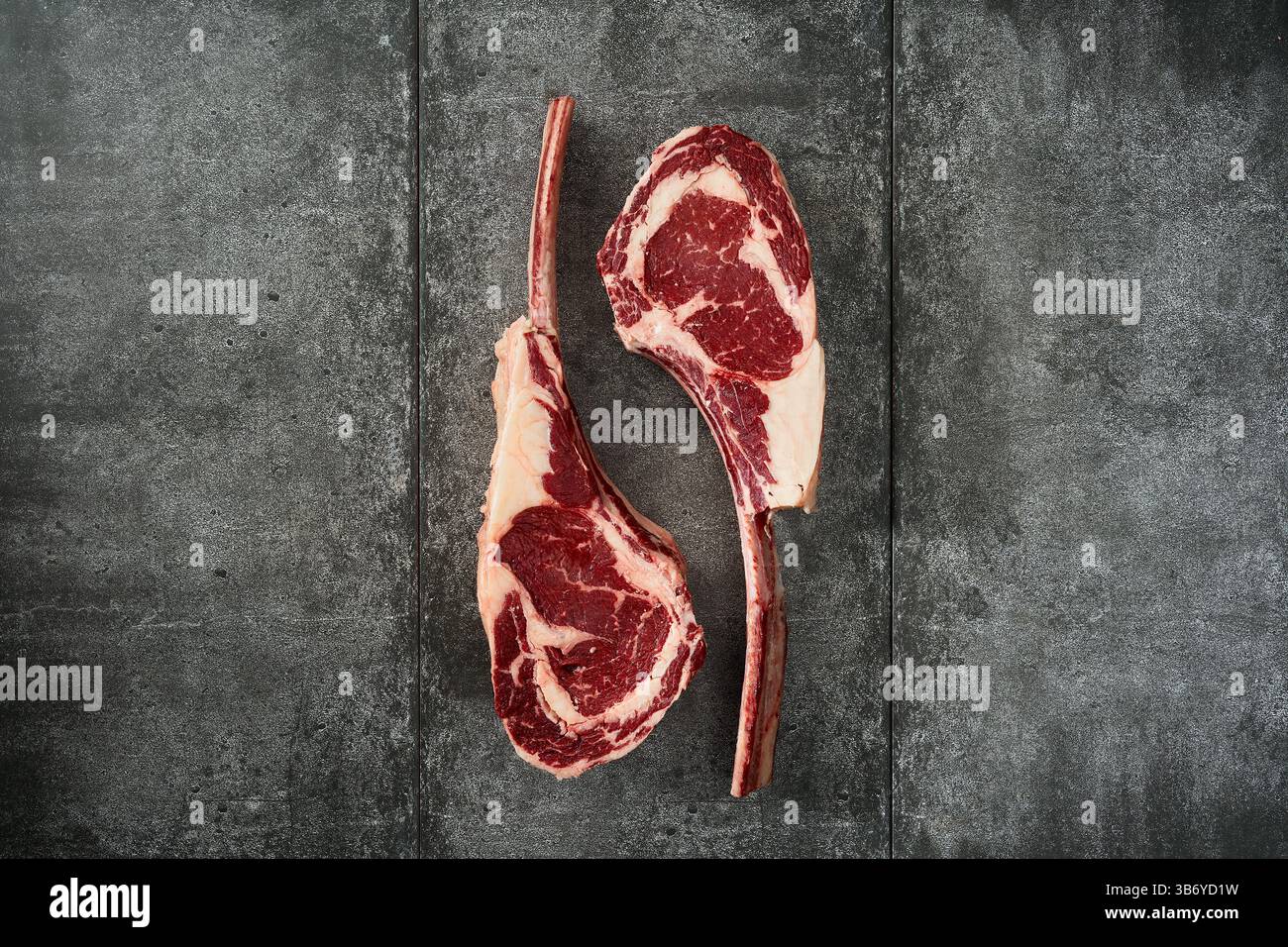 Raw tomahawk steaks on dark stone background Stock Photo