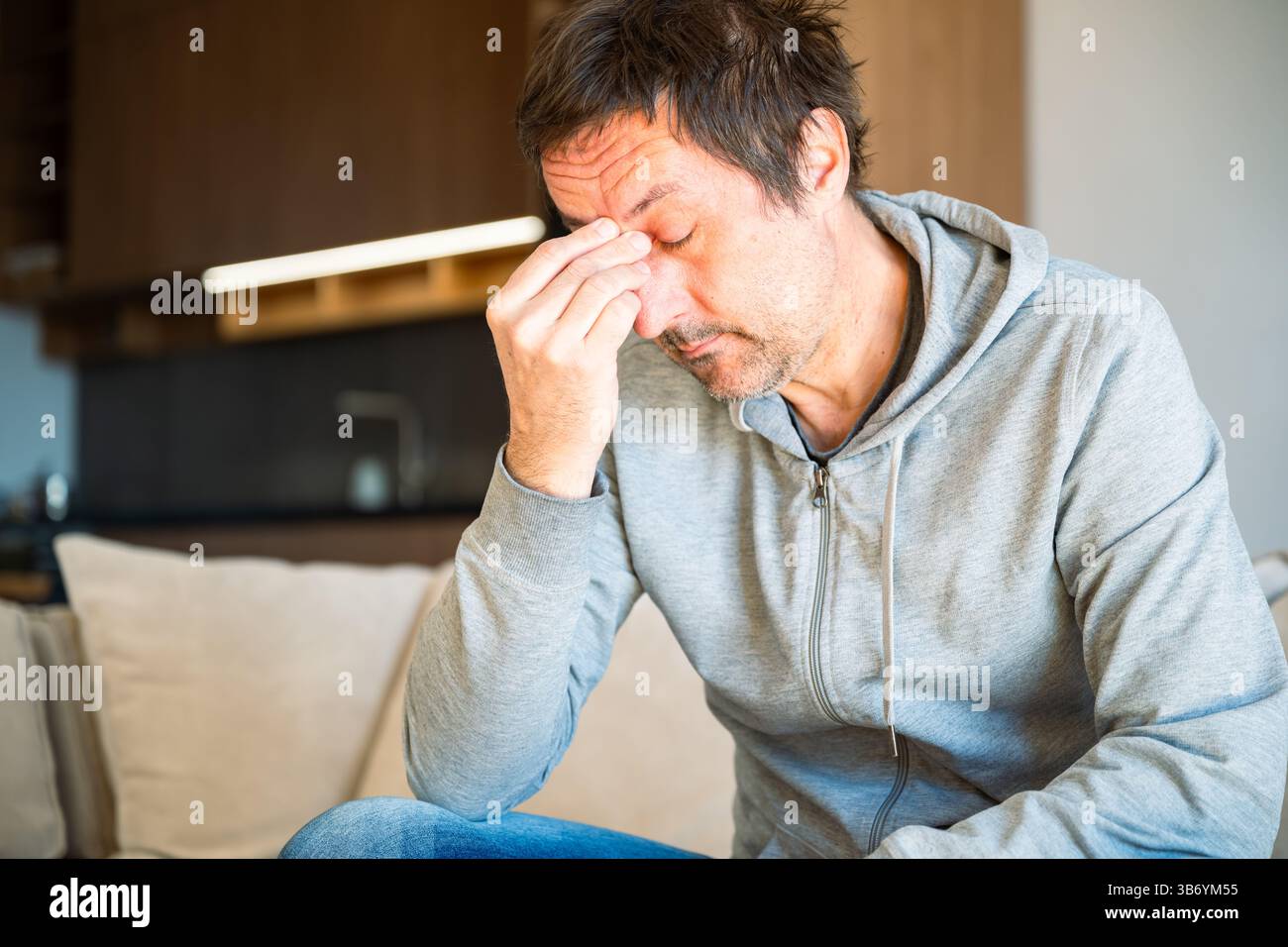 Morning fatigue, sleepy tired man sitting at living room sofa in the morning, selective focus Stock Photo