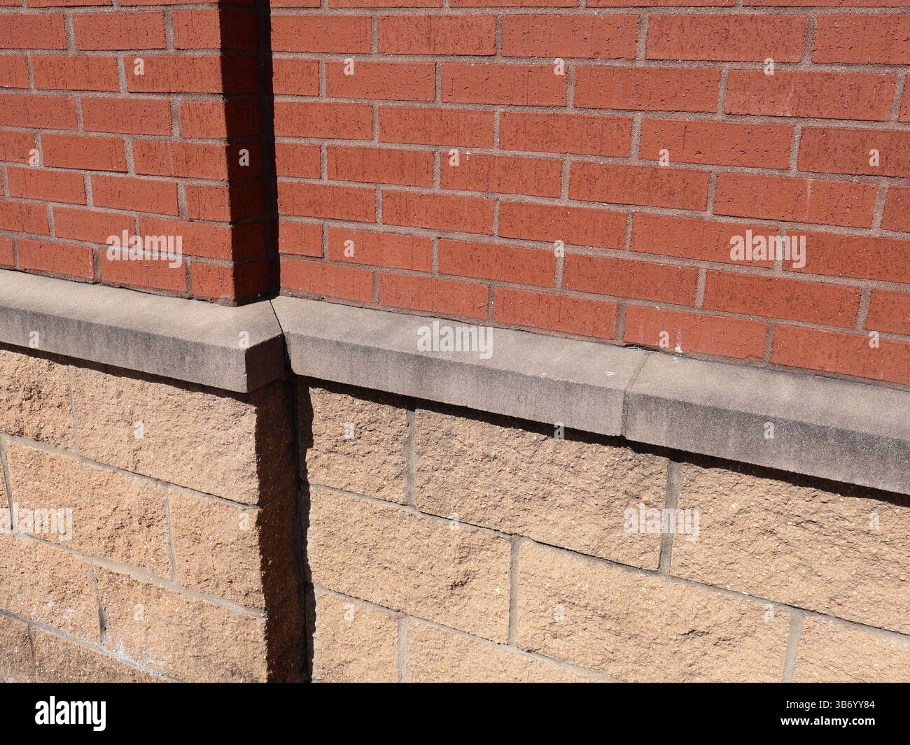 red brick traditional masonry pattern and concrete block wall separated by precast concrete ledge Stock Photo