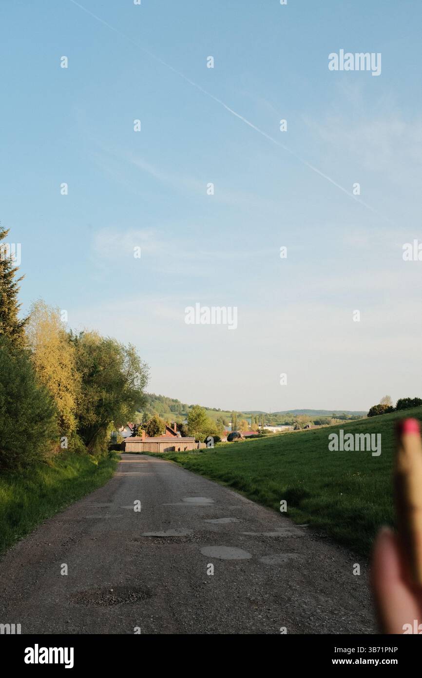 hands holding biscuit sticks or cookies outdoors with green landscape in background during sunny day. High quality photo Stock Photo