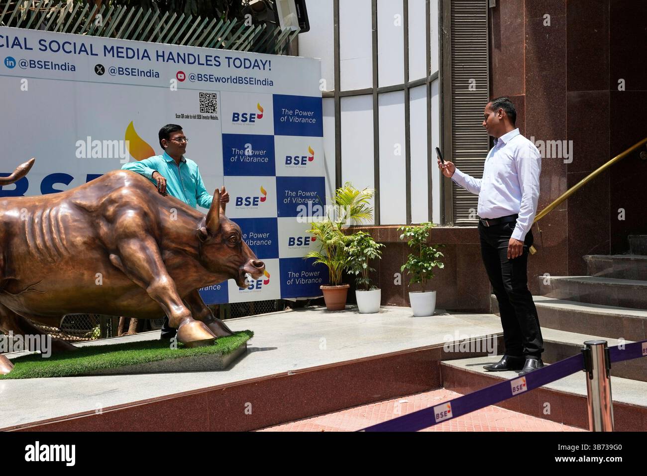 A man poses next to a bull sculpture for a photo outside the Bombay ...