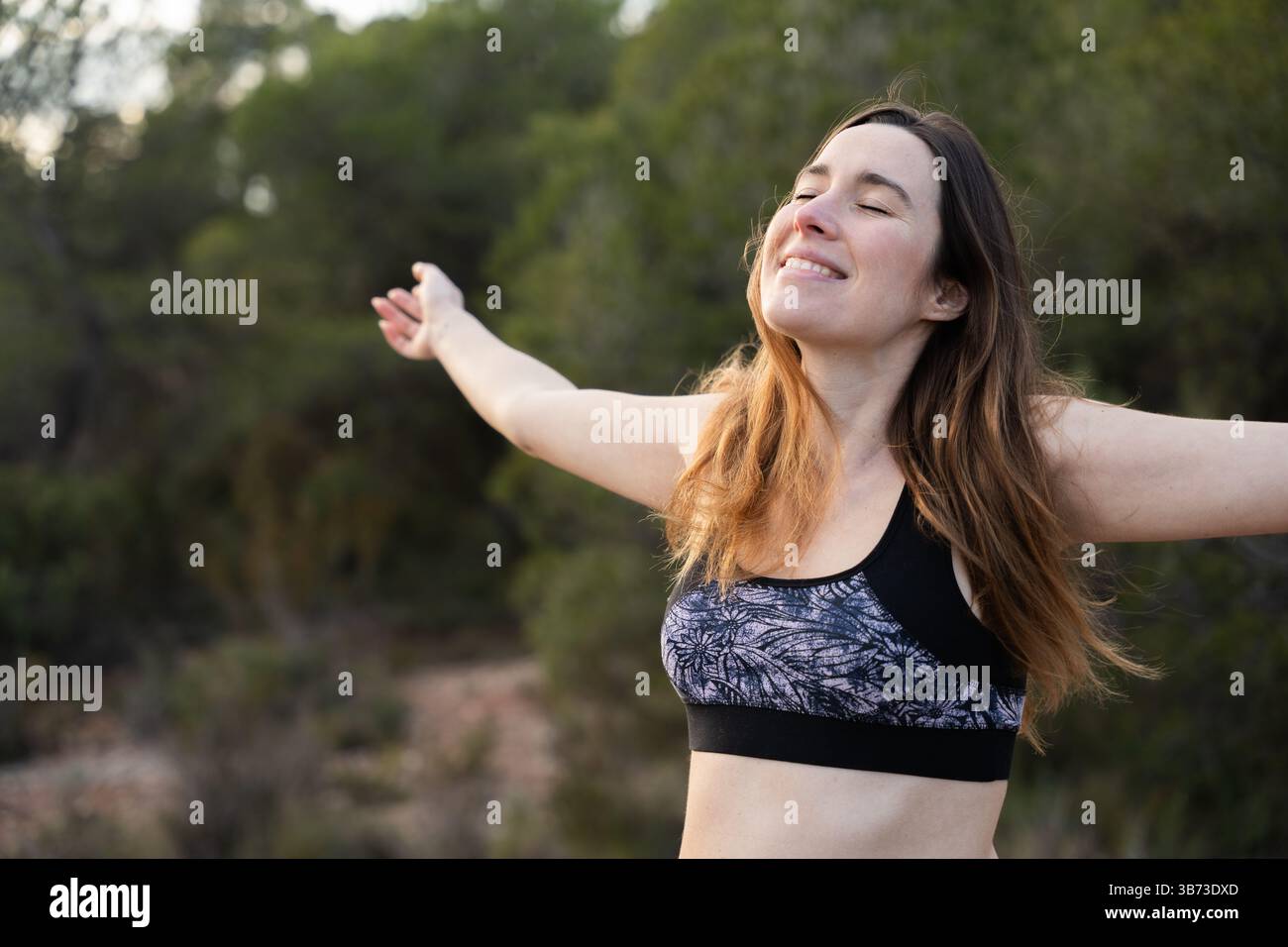 Woman with her eyes closed and her arms open looks happy outdoors Stock ...