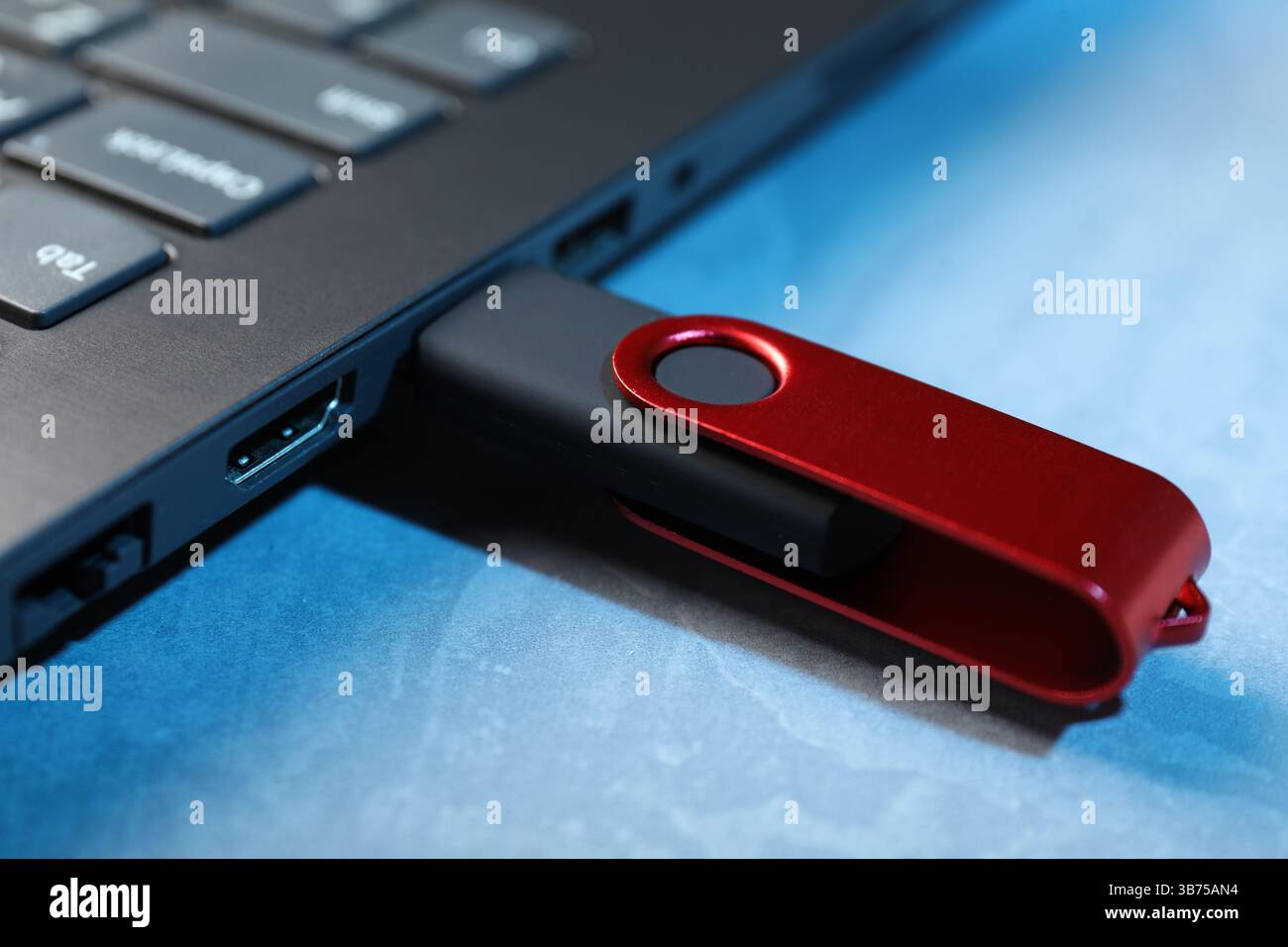Usb flash drive connected to laptop on blue textured table, closeup Stock Photo