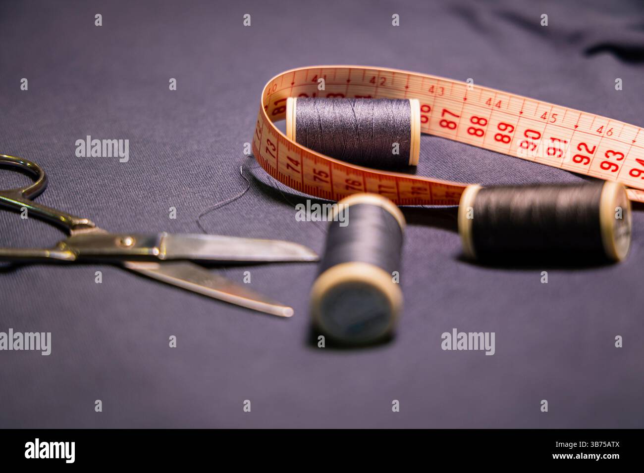 A close-up scene of key sewing instruments-metal scissors, black thread ...