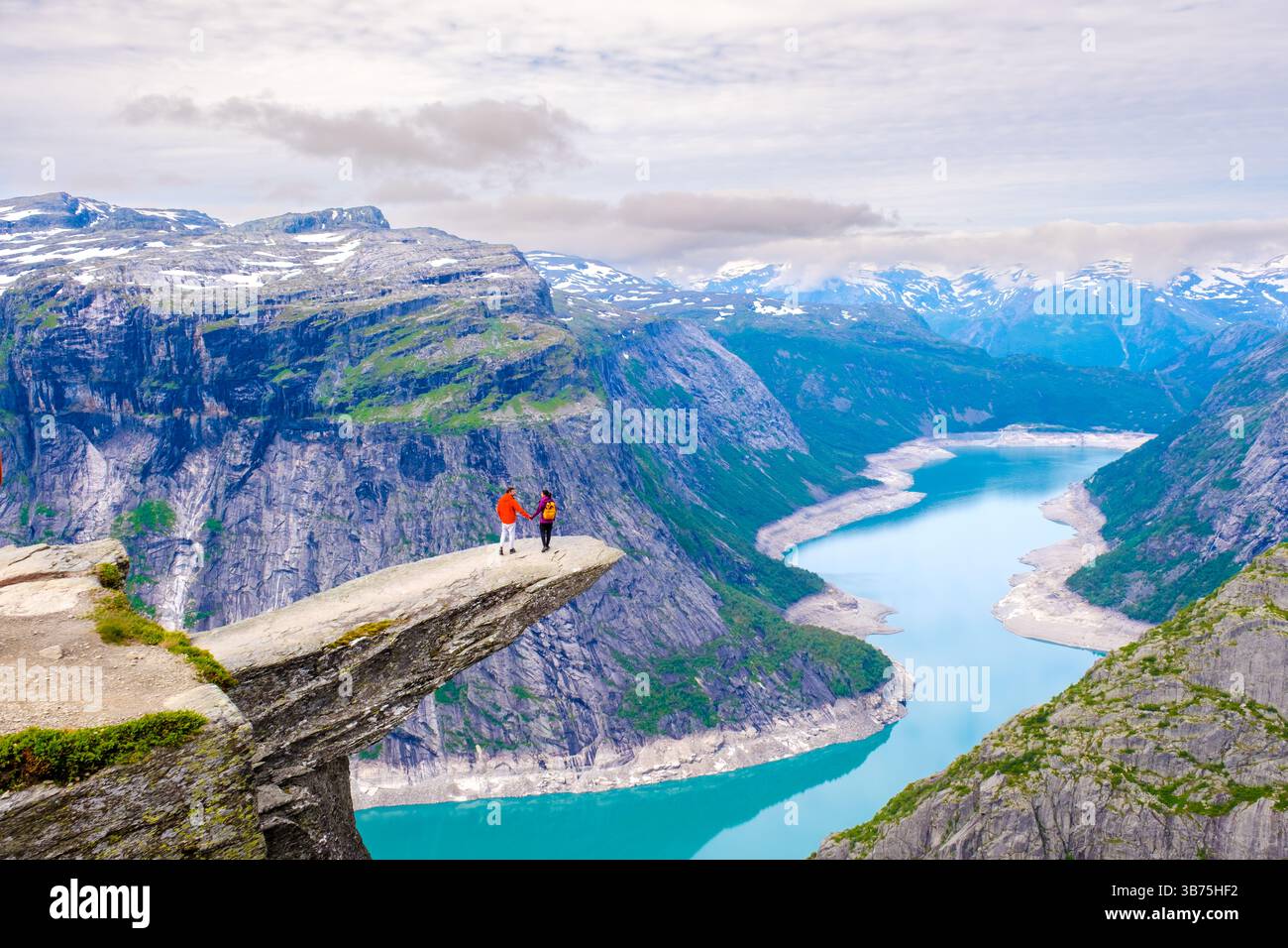 Two adventurers stand on the iconic Trolltunga, Norway rock formation ...