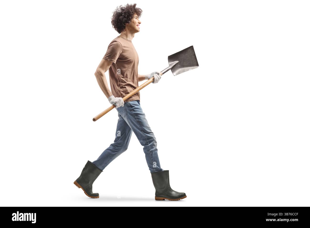 Young man in rubber boots walking and holding a shovel isolated on ...
