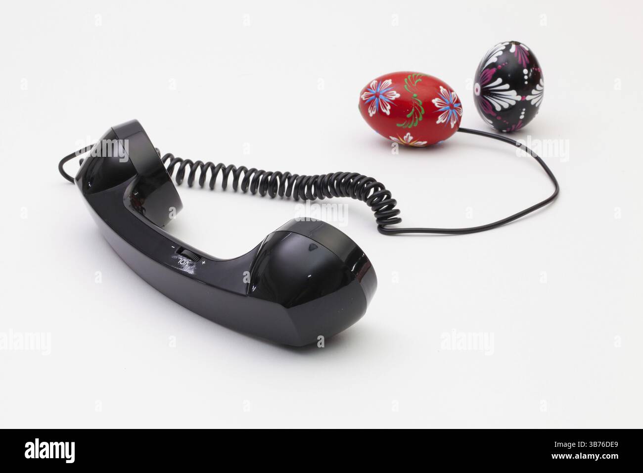 Old phone reciever and cord connection with Easter eggs. Easter hotline concept Stock Photo