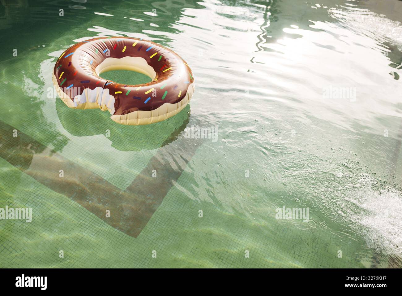 A swimming circle in the form of a bitten doughnut floats in the water ...