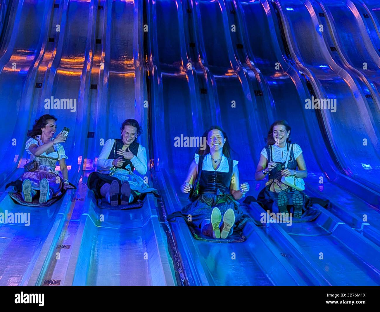 Four women wearing traditional Bavarian dirndls laugh and capture ...