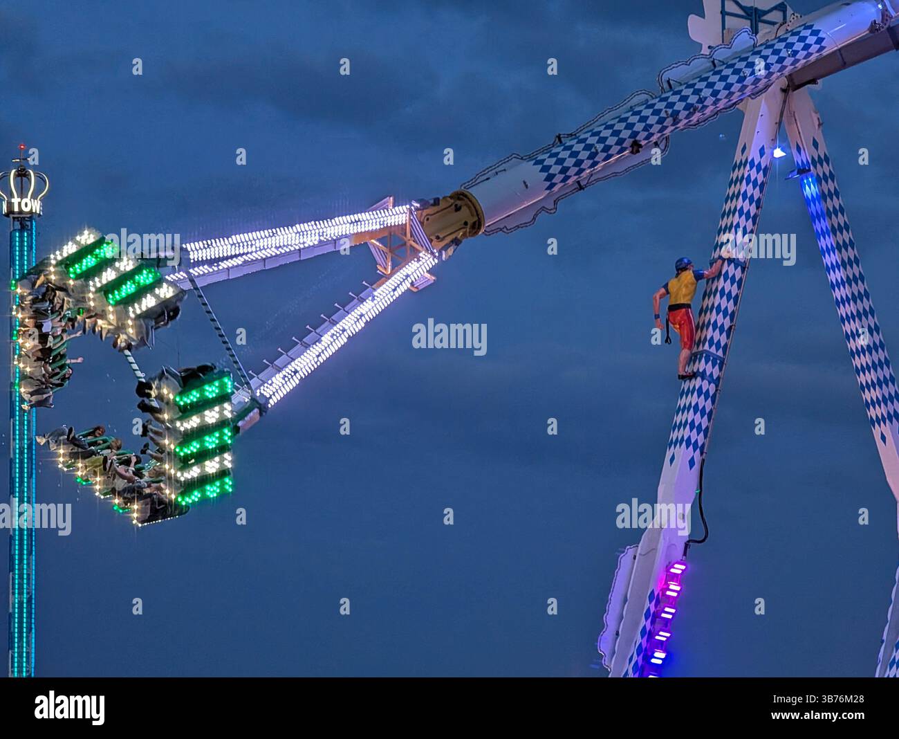 Brightly lit thrill ride swings passenderes through the air at a fun ...