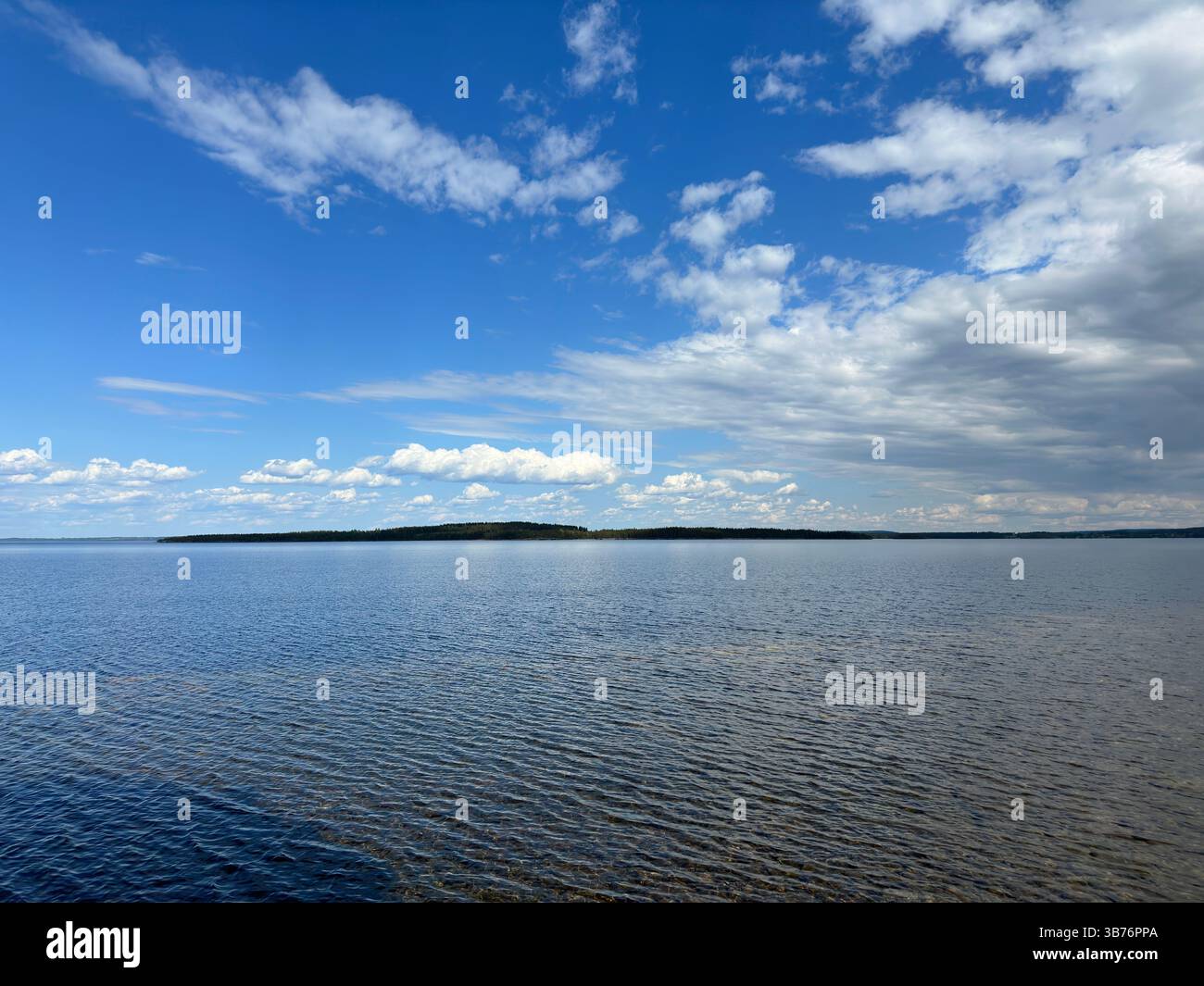 A beautiful landscape of a calm lake under a vibrant blue sky with fluffy clouds. - Smartphone Captured Stock Image