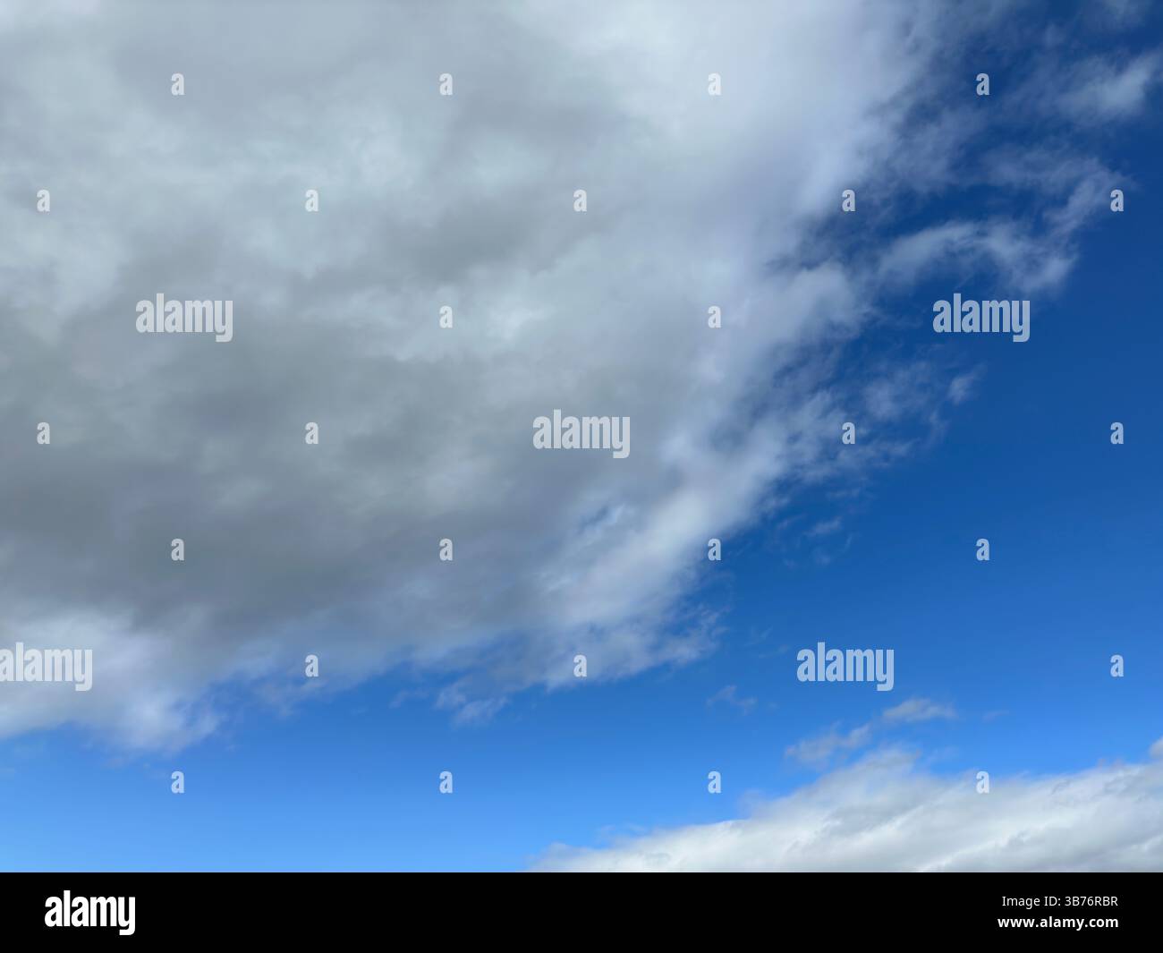 The bright blue sky is filled with soft, billowy white clouds, creating a beautiful view. - Smartphone Captured Stock Image