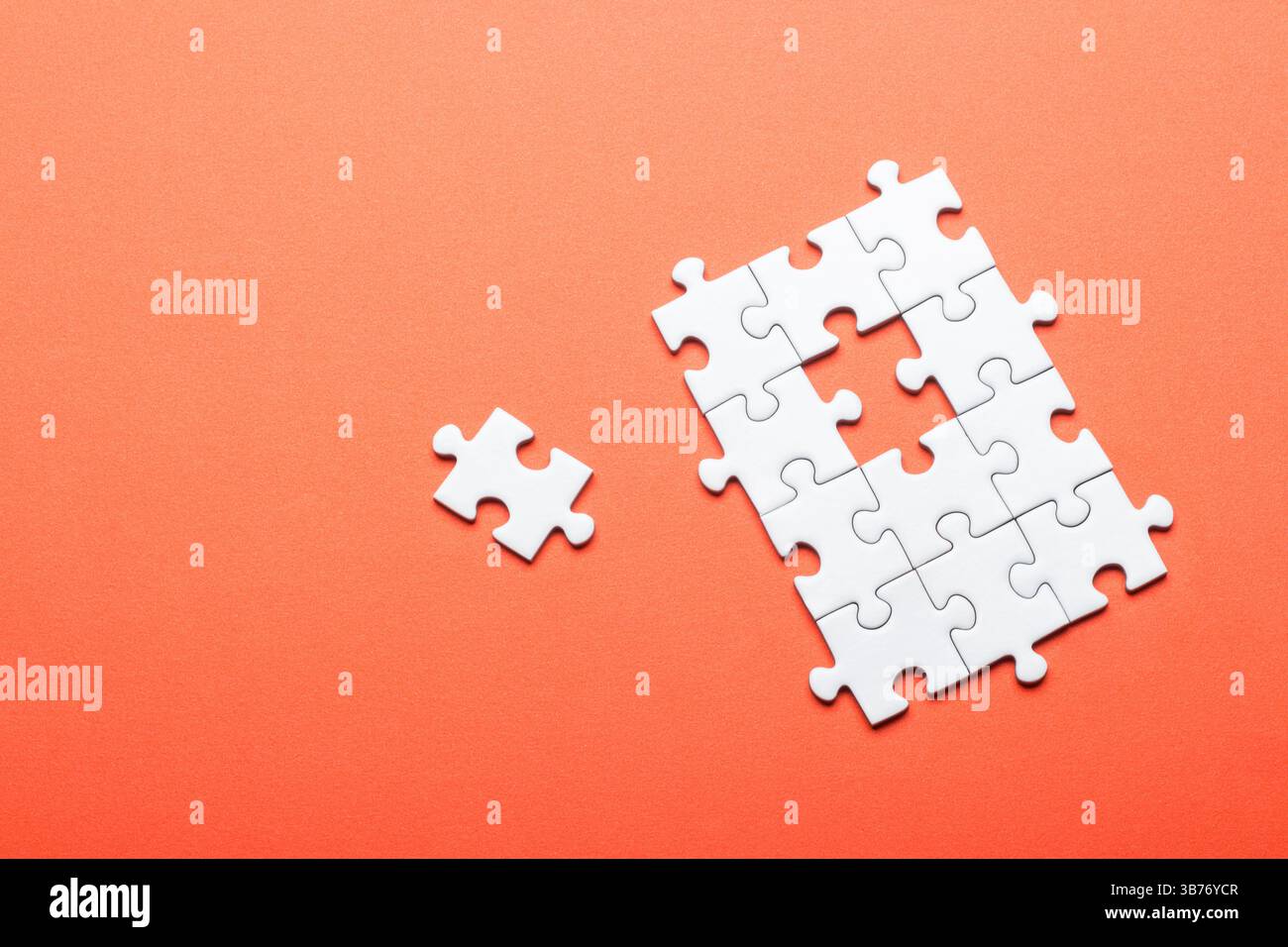 White puzzle with missing piece on bright orange background Stock Photo
